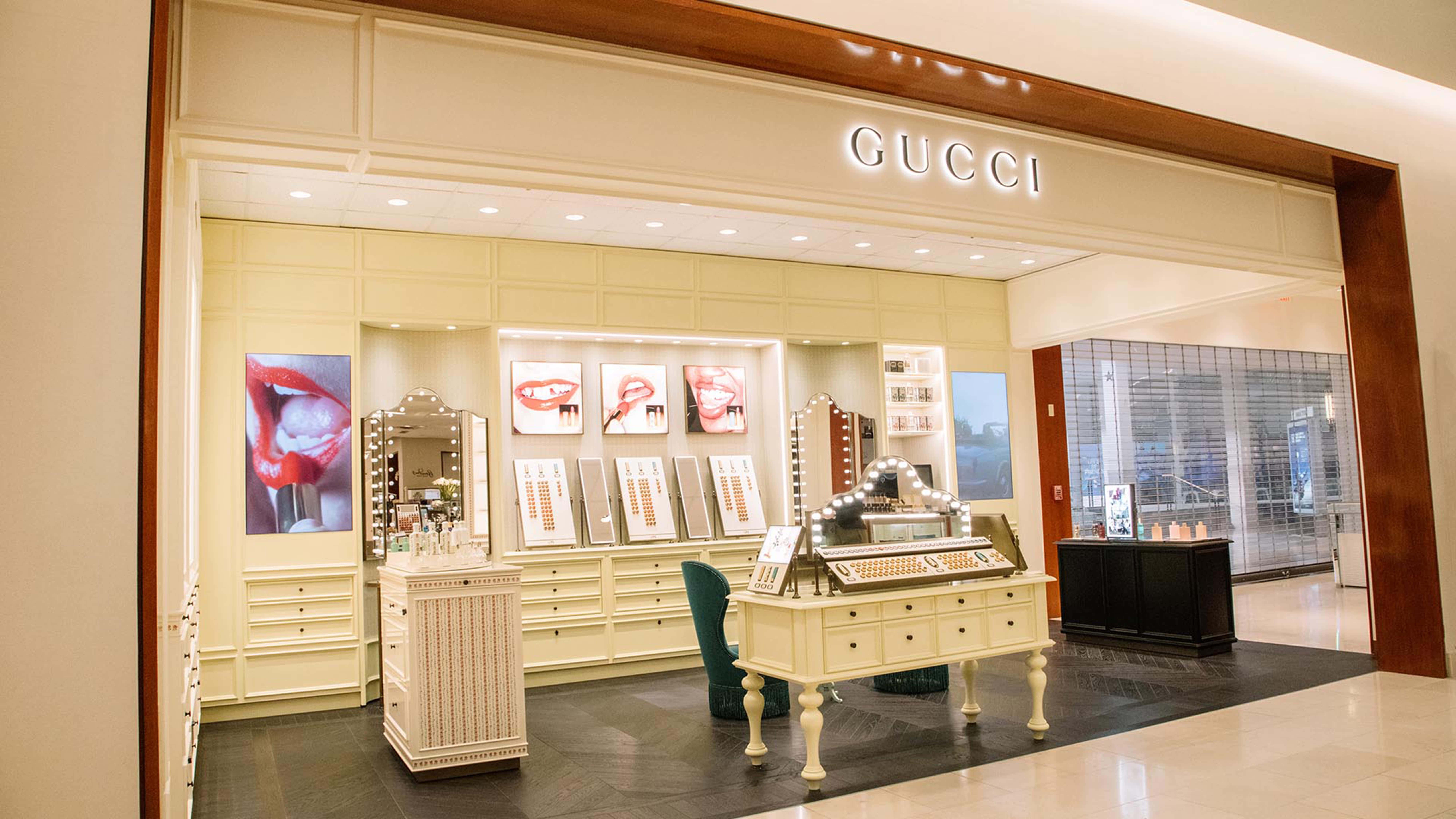 高清 桌布 壁紙 — 豪華Gucci店內裝潢，奶油色牆壁、玻璃陳列櫃和優雅家具，展示高端化妝品和珠寶。