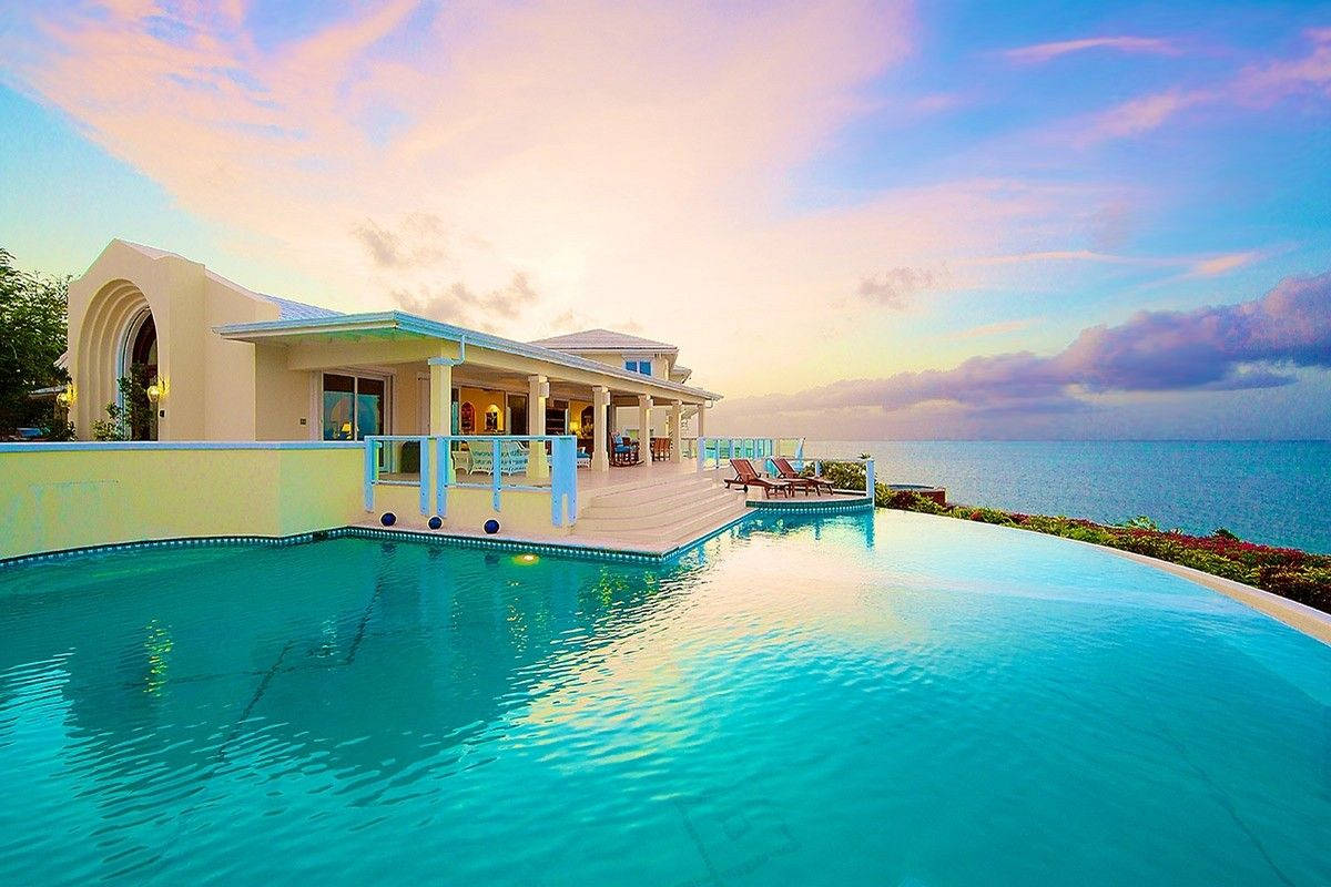 Turks And Caicos 桌布 壁紙 — 豪華別墅設有無邊際泳池，可欣賞日落時分的海洋，天空呈現鮮豔的粉紅色和藍色。