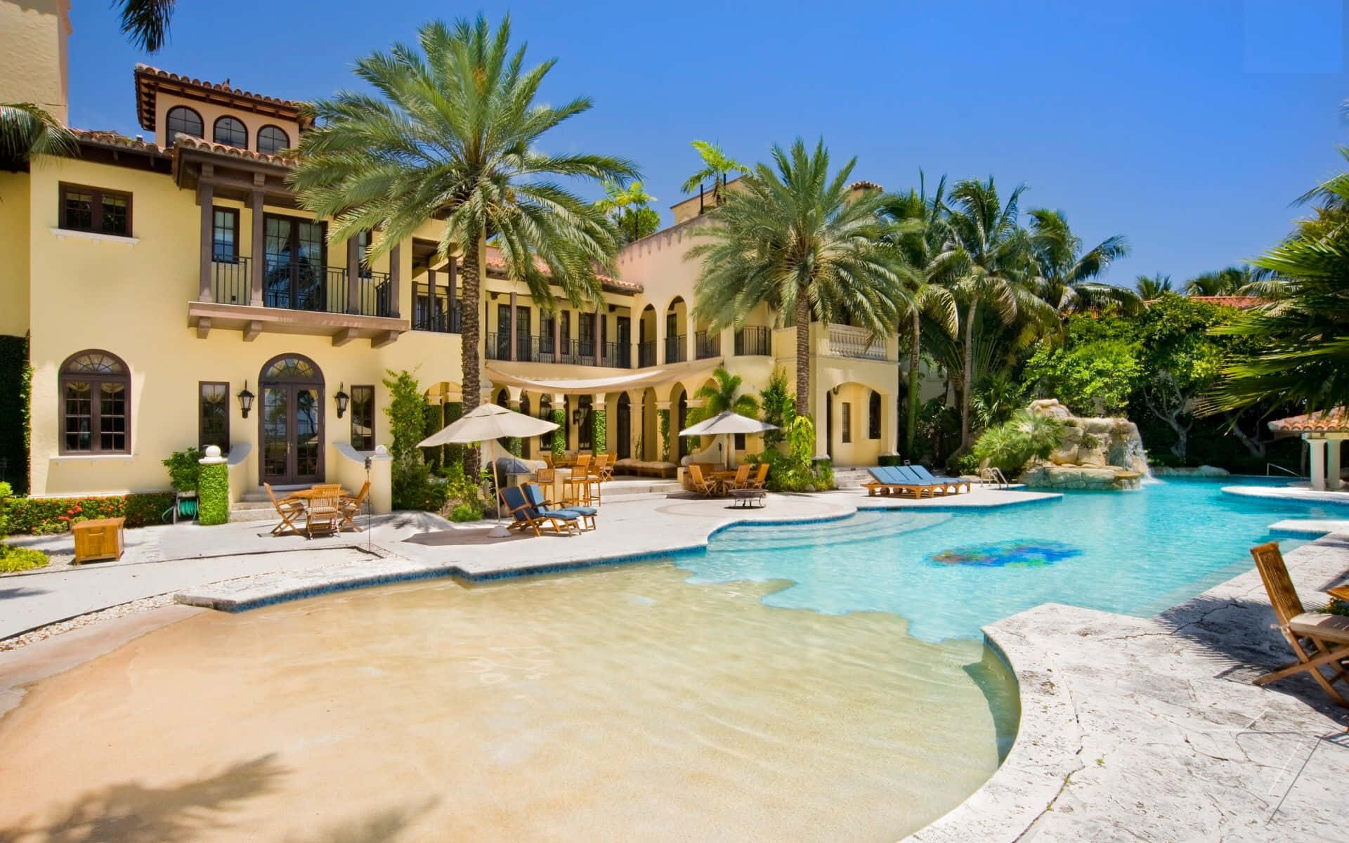 Mansion 桌布 壁紙 — 豪華地中海風格別墅，棕櫚樹和閃閃發光的游泳池，在明亮的藍天下。