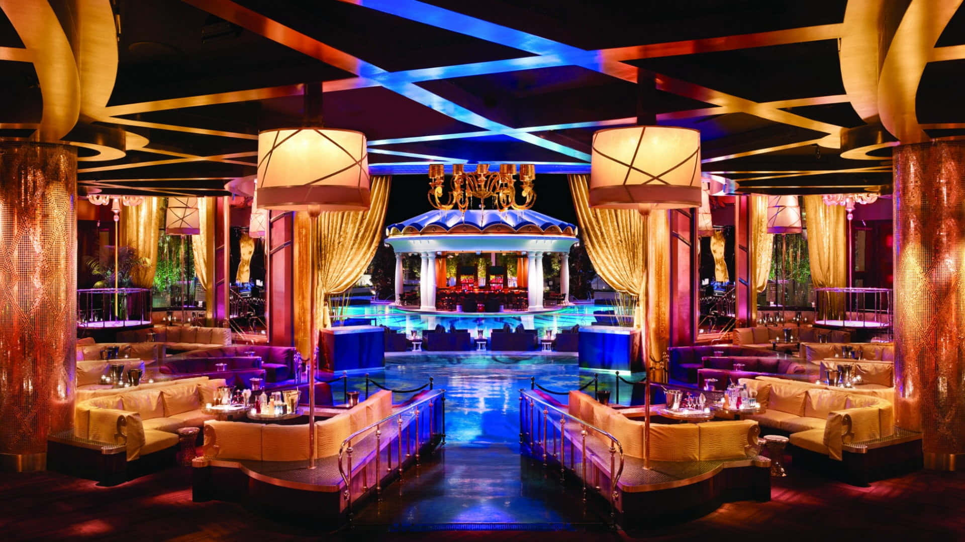Nightclub 桌布 壁紙 — 豪華夜總會，設有發光藍色泳池舞台，周圍是毛絨座椅，上方是幾何天花板燈光。
