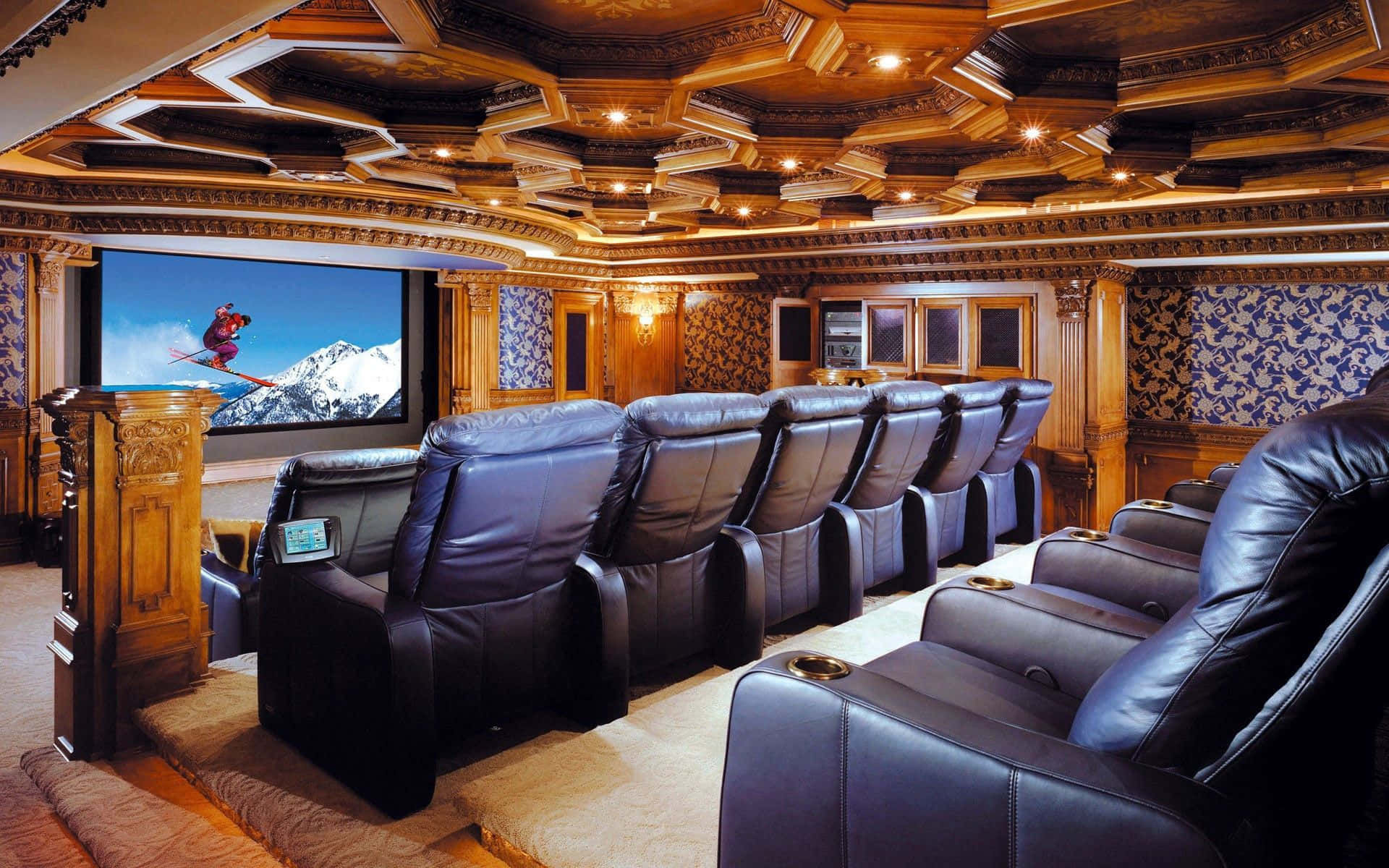 Home Cinema 桌布 壁紙 — 豪華家庭劇院，一排排黑色皮革躺椅面向大螢幕，螢幕上顯示藍天下雪峰上的滑雪者。