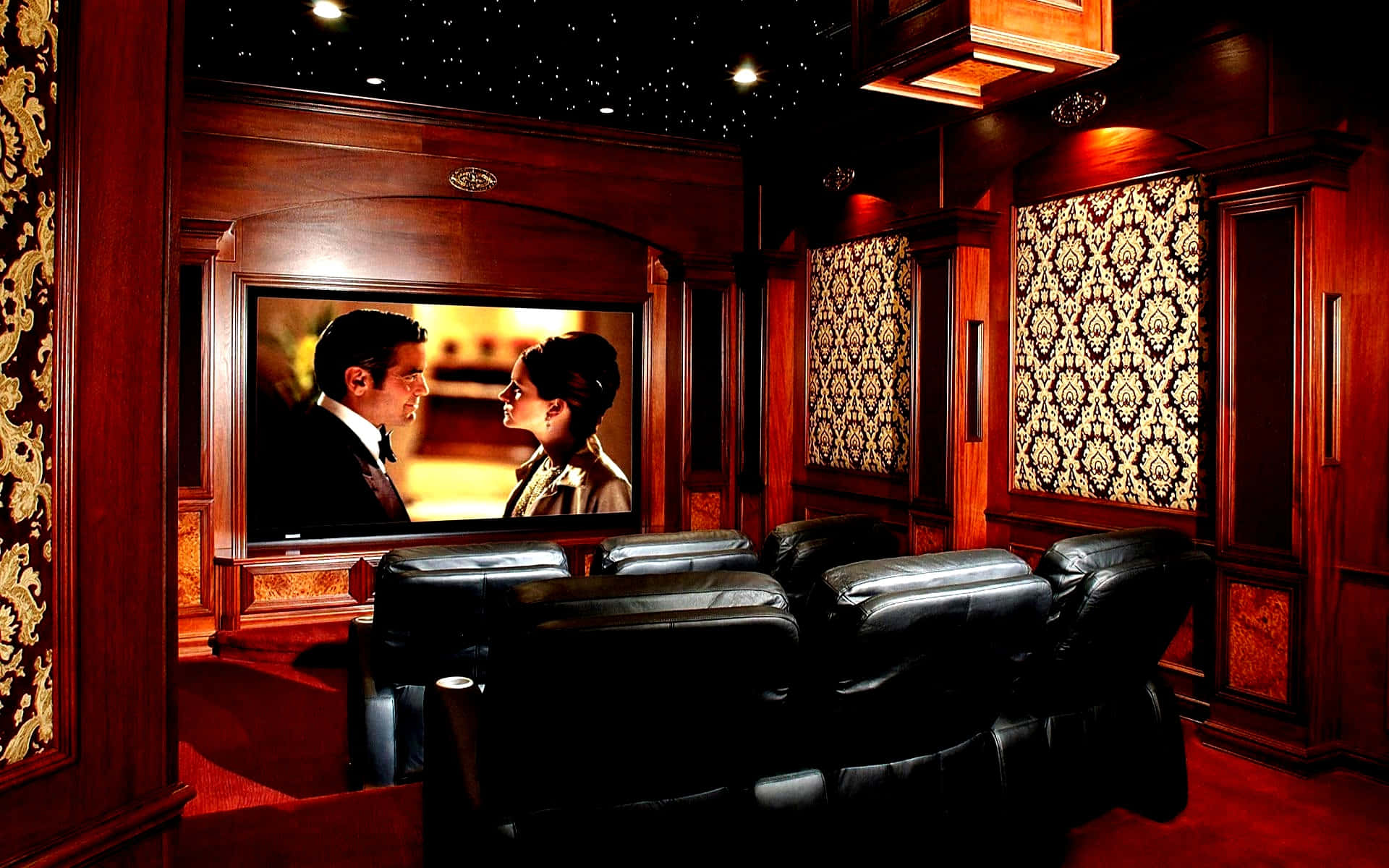 Home Cinema 桌布 壁紙 — 豪華家庭劇院，配有豐富的木鑲板、黑色皮革躺椅，以及大螢幕上方的星空天花板，顯示浪漫場景。