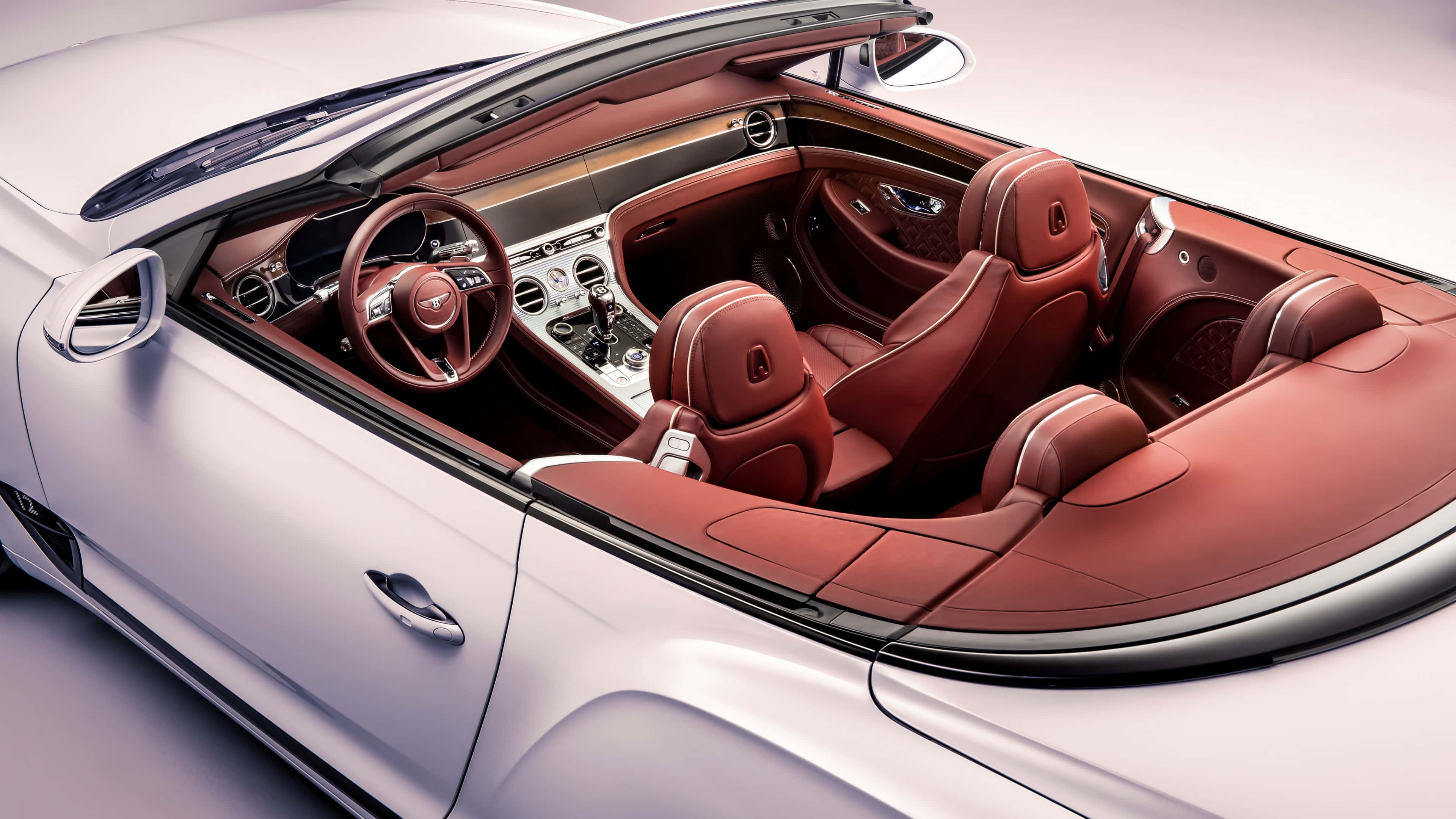 Bentley Continental Gt Convertible 桌布 壁紙 — 豪華敞篷車內裝，配以豐富的紅色皮革座椅和銀色飾邊，在攝影棚燈光下。