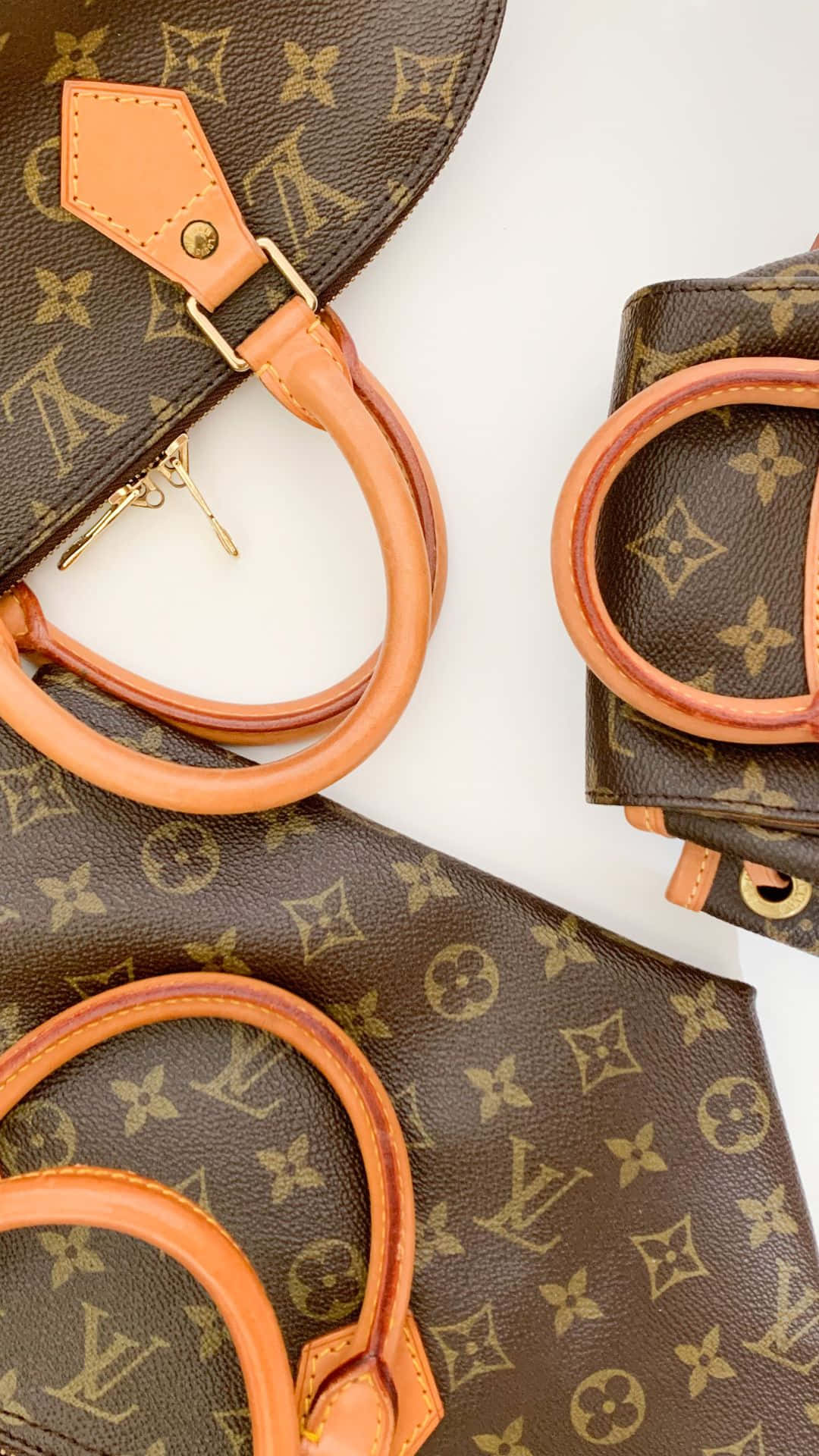 louis vuitton phone 桌布 壁紙 — 豪華棕色字母組合手提包，配有棕褐色皮革手柄，整齊排列在潔白表面上。