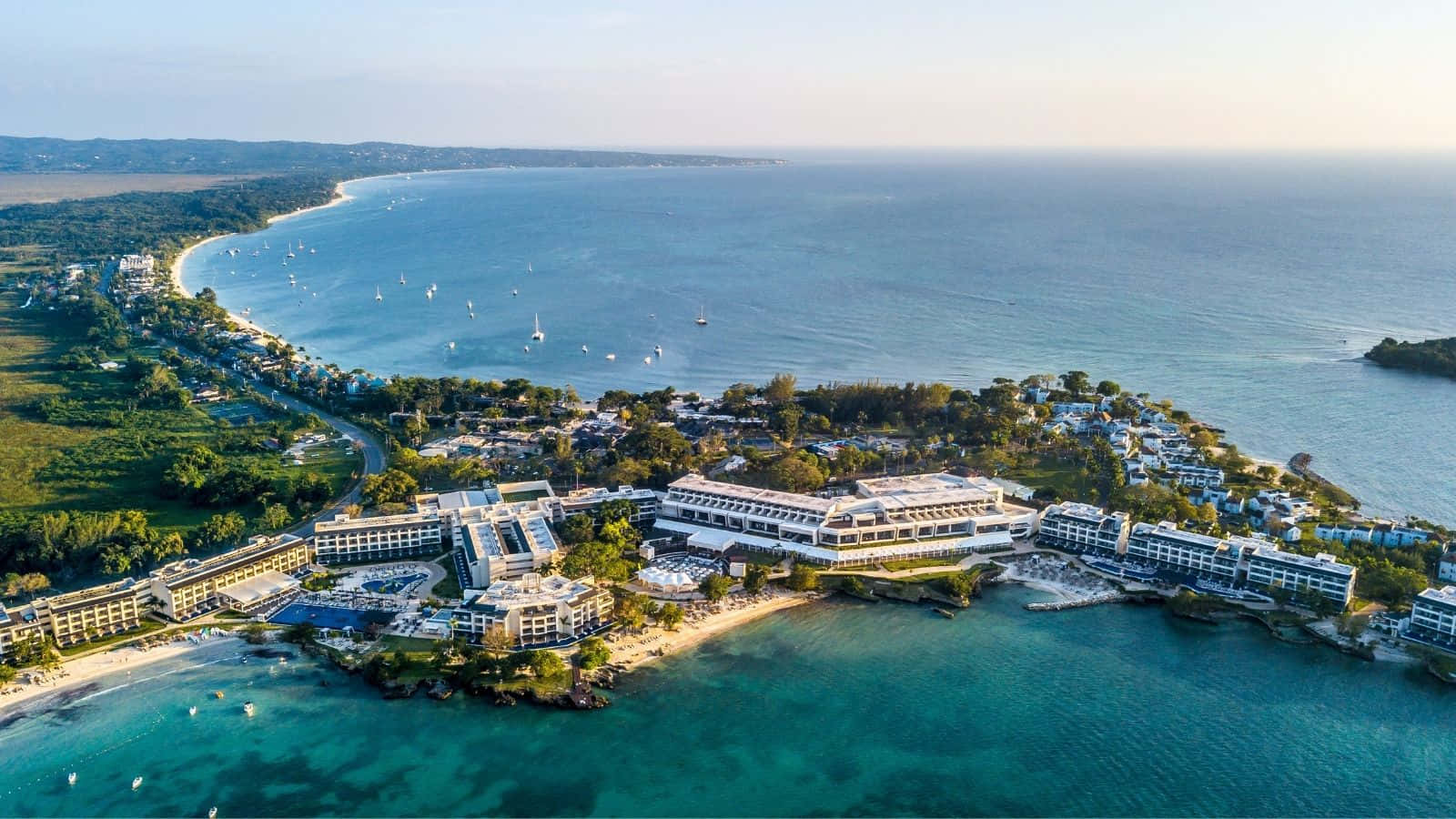 Jamaican Island 桌布 壁紙 — 豪華海岸度假村的鳥瞰圖，碧綠的海水點綴著帆船，海岸線綠意盎然。