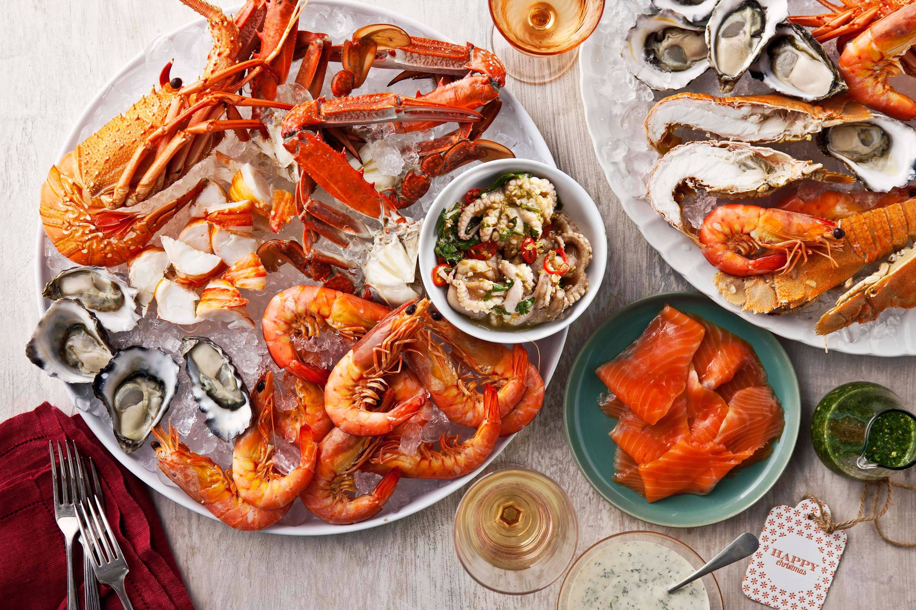 Seafood 桌布 壁紙 — 豪華海鮮拼盤，包括龍蝦、蝦、生蠔和鮭魚，放在冰上，配以酒杯和蘸醬。