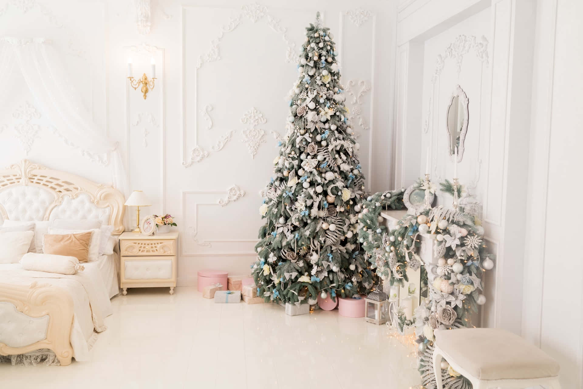 Aesthetic Christmas Tree 桌布 壁紙 — 豪華白色臥室中，一張大床旁擺放著裝飾有銀色和柔和色調飾品的華麗聖誕樹。