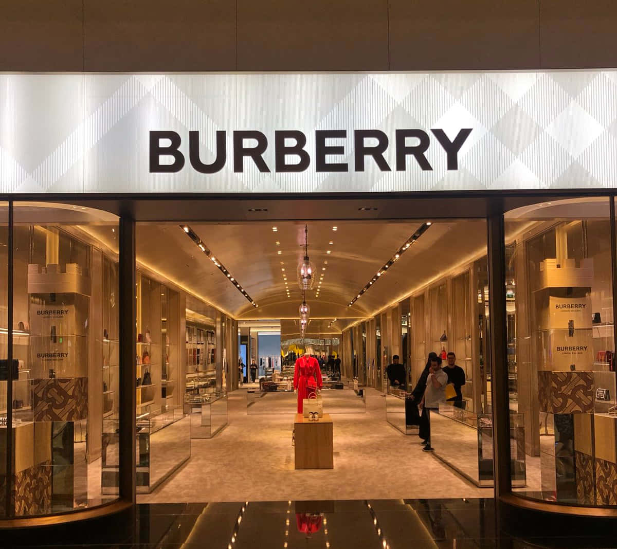 Burberry 桌布 壁紙 — 豪華的 Burberry 商店入口，配有玻璃門、溫暖的燈光，中央有一個紅色人體模型。