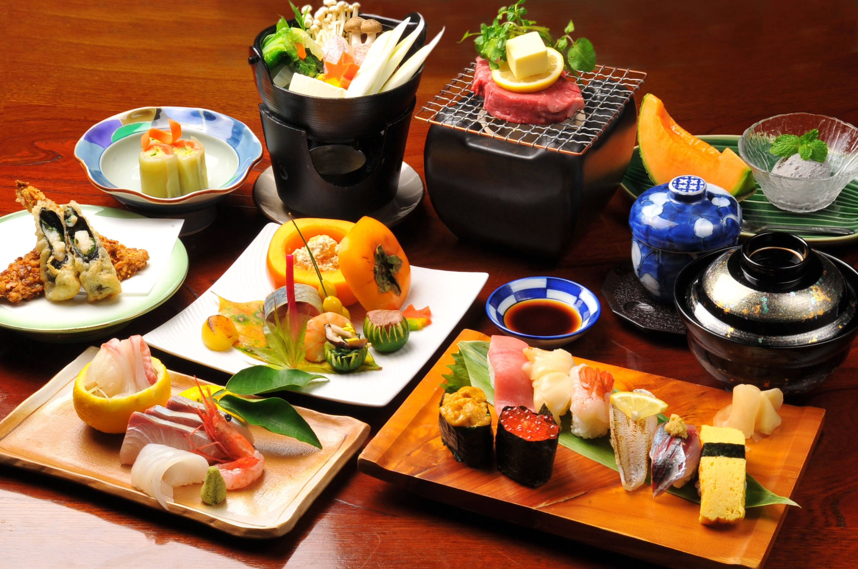中文 桌布 壁紙 — 豪華的日本料理擺盤，包括壽司、刺身、天婦羅和烤肉，擺放在木托盤和陶瓷盤上。
