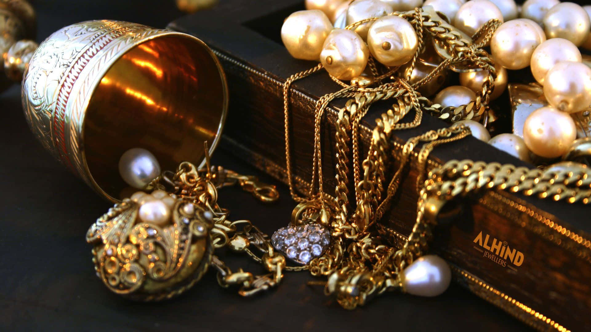 Jewelry Design 桌布 壁紙 — 豪華的金飾和珍珠從一個裝飾盒中溢出，落在深色木質表面上。