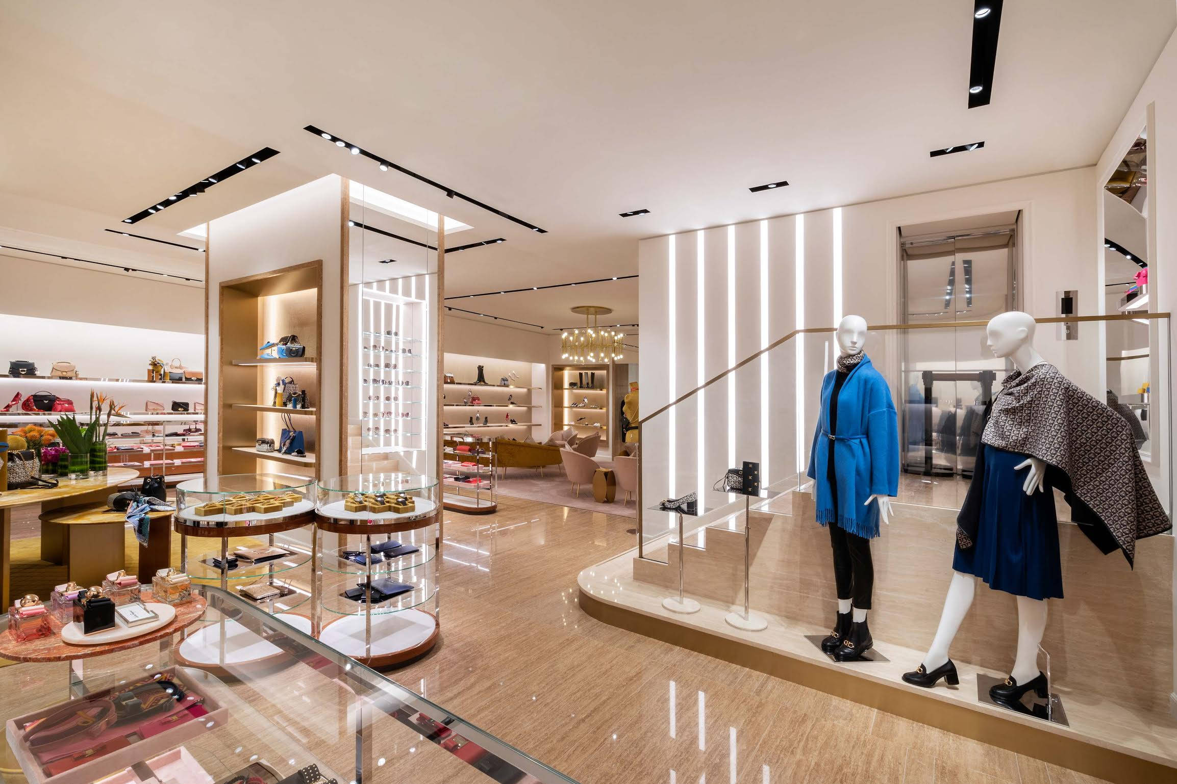 Ferragamo 桌布 壁紙 — 豪華精品店內部，設有穿著藍色服裝的人體模型、玻璃展示櫃和溫暖的環境照明。