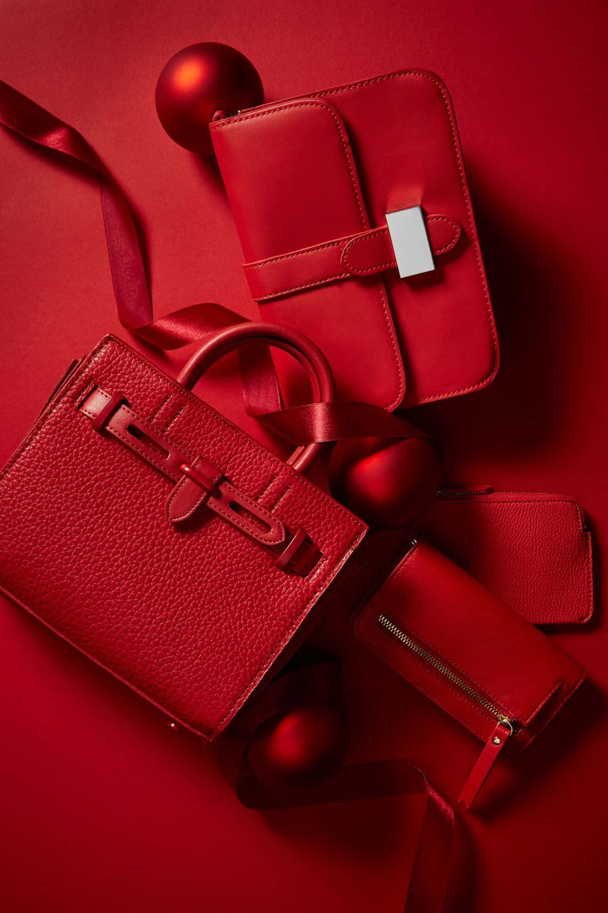Red Handbag 桌布 壁紙 — 豪華紅色皮革手提包及配件，搭配緞帶和裝飾品，優雅地陳列在濃郁的紅色背景上。