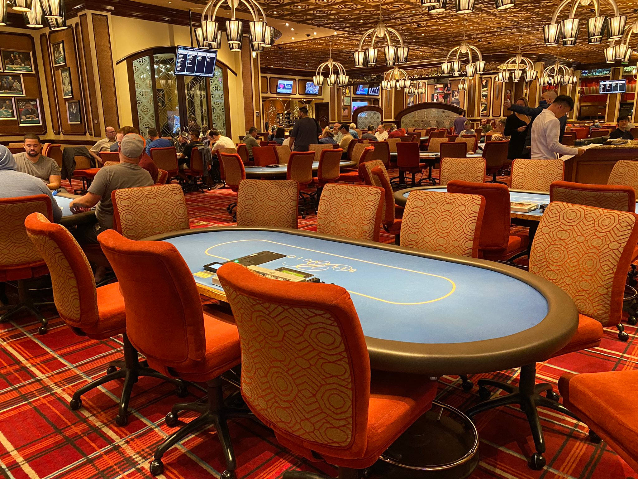 Poker 桌布 壁紙 — 豪華賭場撲克室，玩家圍坐在藍色毛氈桌旁，上方是華麗吊燈。