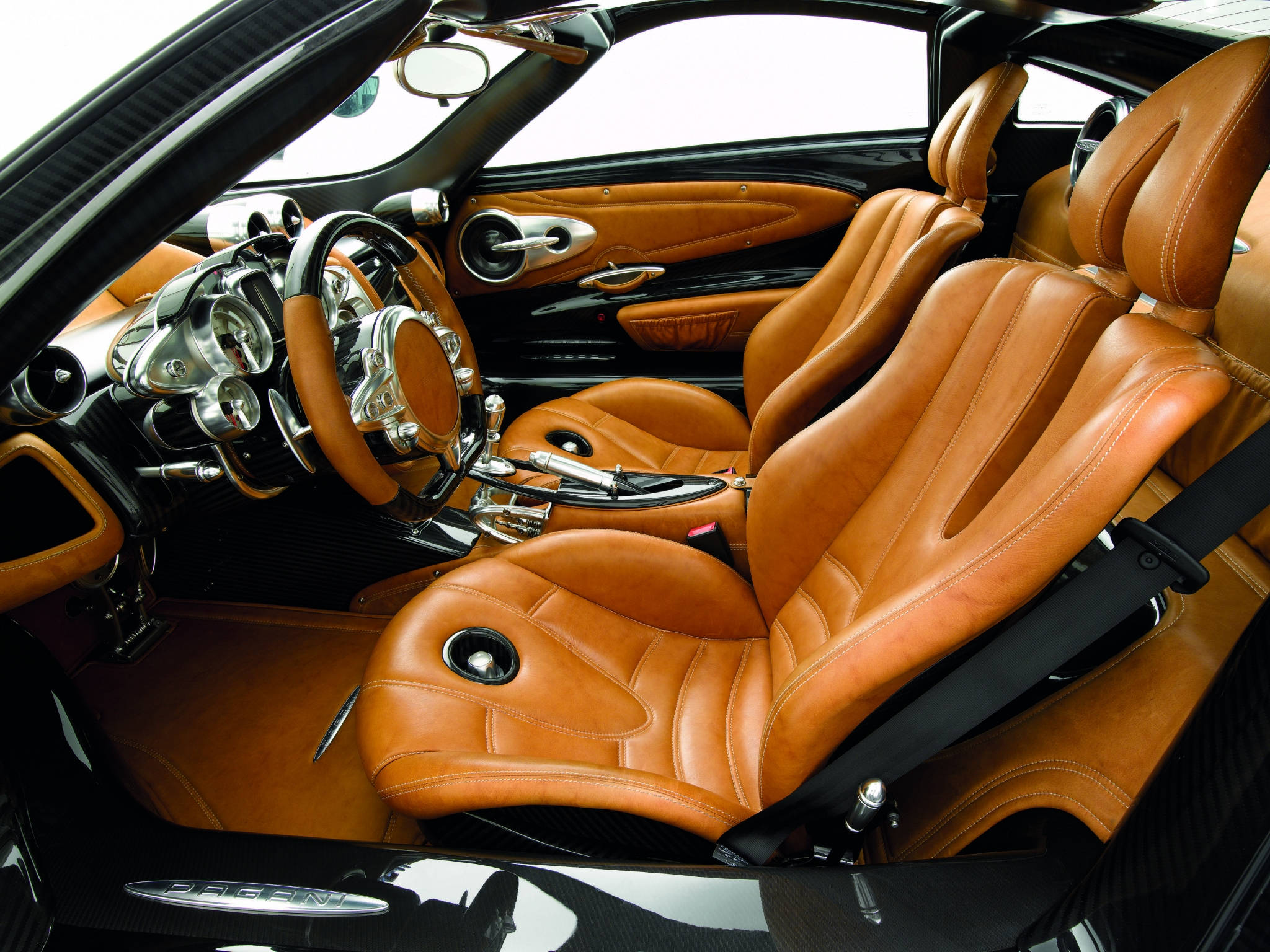 Pagani 桌布 壁紙 — 豪華跑車內裝，配備棕褐色皮革座椅和碳纖維飾邊，在明亮的日光下。