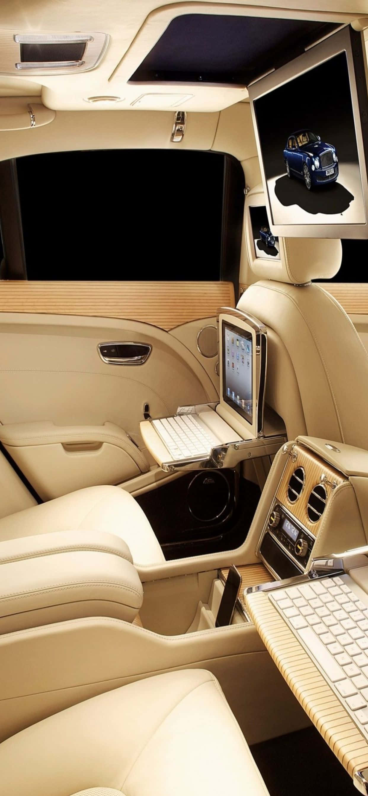 iPhone Xs Max Bentley 桌布 壁紙 — 豪華車內裝，配備奶油色皮革座椅和為後排乘客設計的內置筆記型電腦桌。