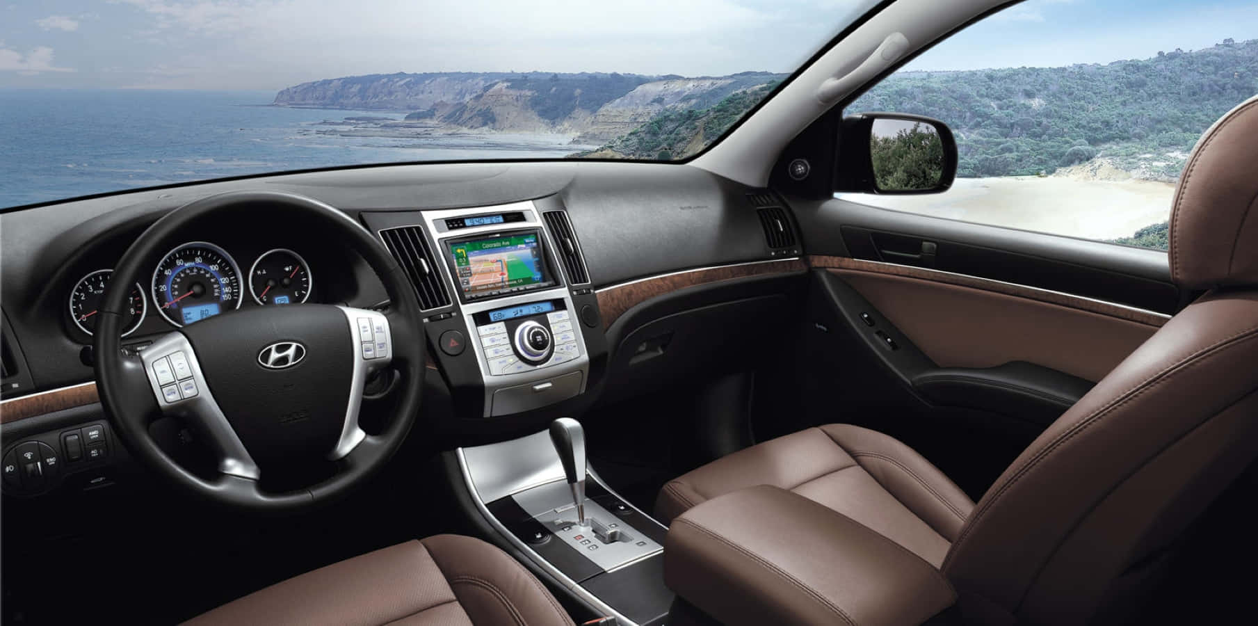 Hyundai Veracruz 桌布 壁紙 — 豪華車內裝，配備棕褐色皮革座椅和木質飾邊，俯瞰海岸懸崖和海洋。
