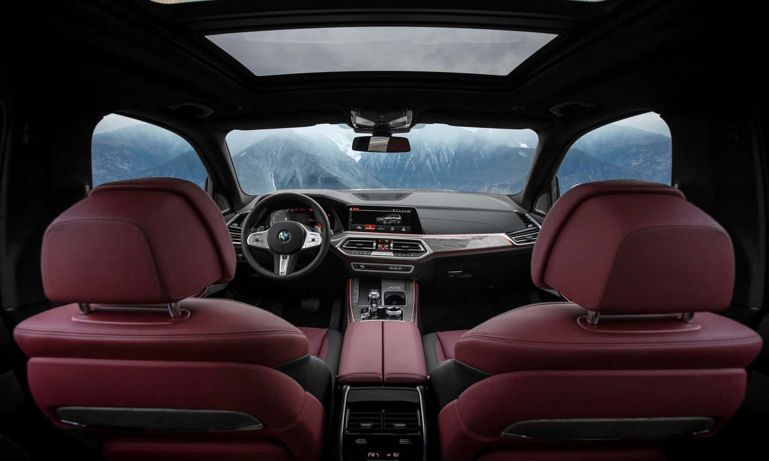 Bmw X5 桌布 壁紙 — 豪華車內裝，配備紅色皮革座椅，透過全景玻璃車頂欣賞山景。