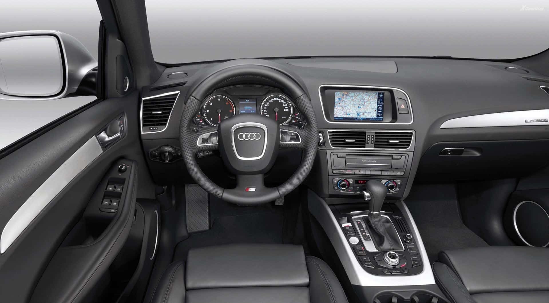 Audi Q5 桌布 壁紙 — 豪華車內裝，配備黑色皮革座椅、銀色飾邊和數位導航螢幕。