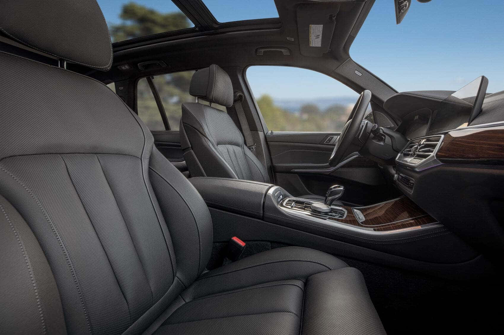Bmw X5 桌布 壁紙 — 豪華車內裝，配備黑色皮革座椅和木質飾邊，在明亮的日光下展現頂級工藝。