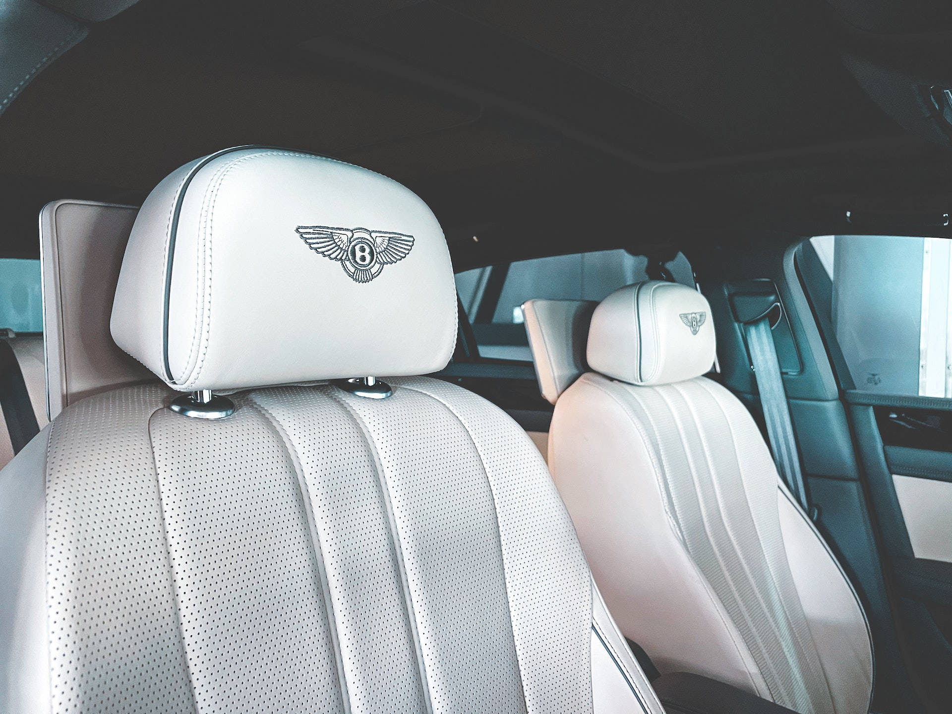Bentley Cars 桌布 壁紙 — 豪華車內裝，配有白色穿孔皮革座椅和頭枕上的 Bentley 翼形 'B' 標誌。