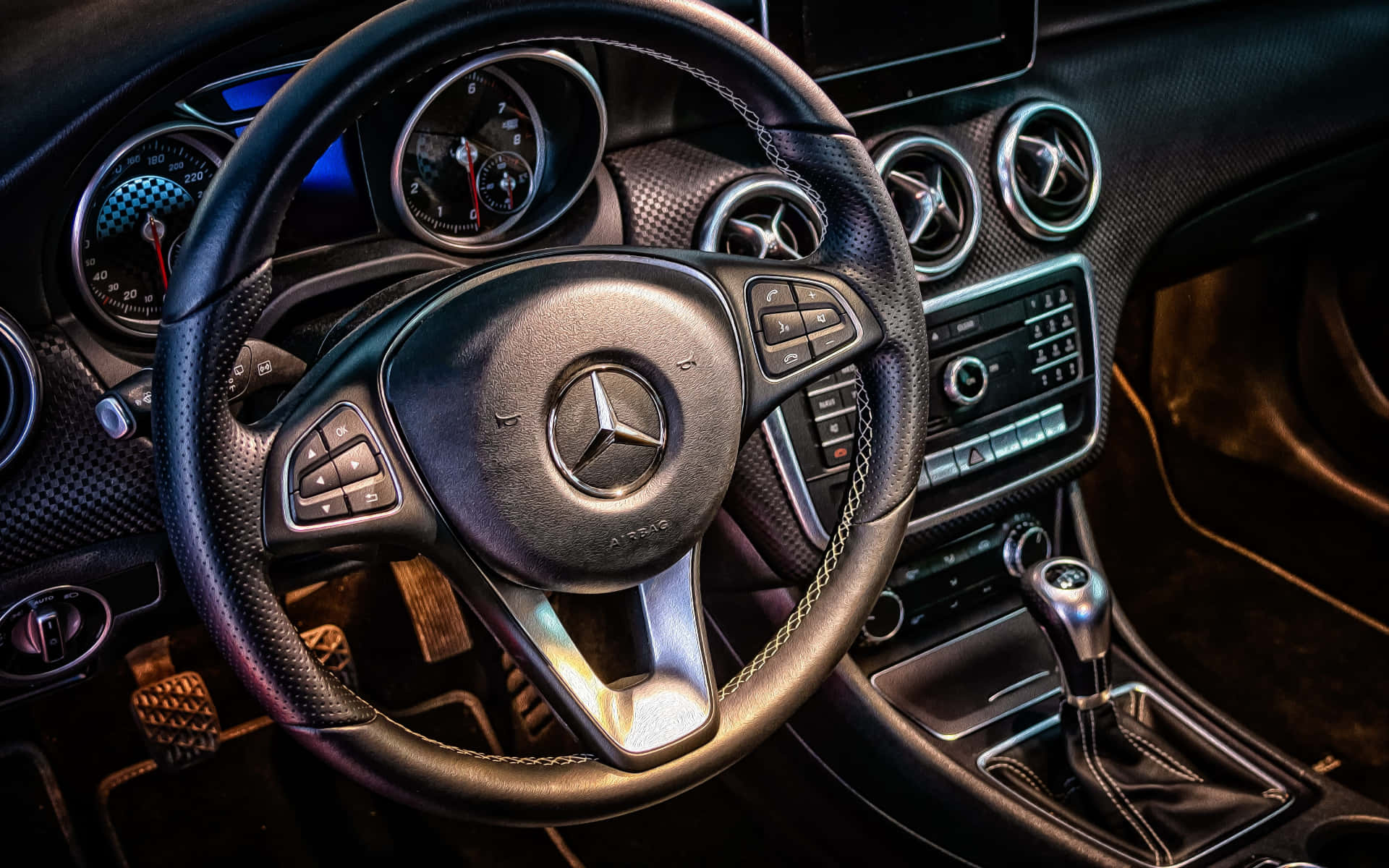 gear 桌布 壁紙 — 豪華車內裝特寫，黑色皮革方向盤帶有 Mercedes-Benz 標誌和發光儀表組。