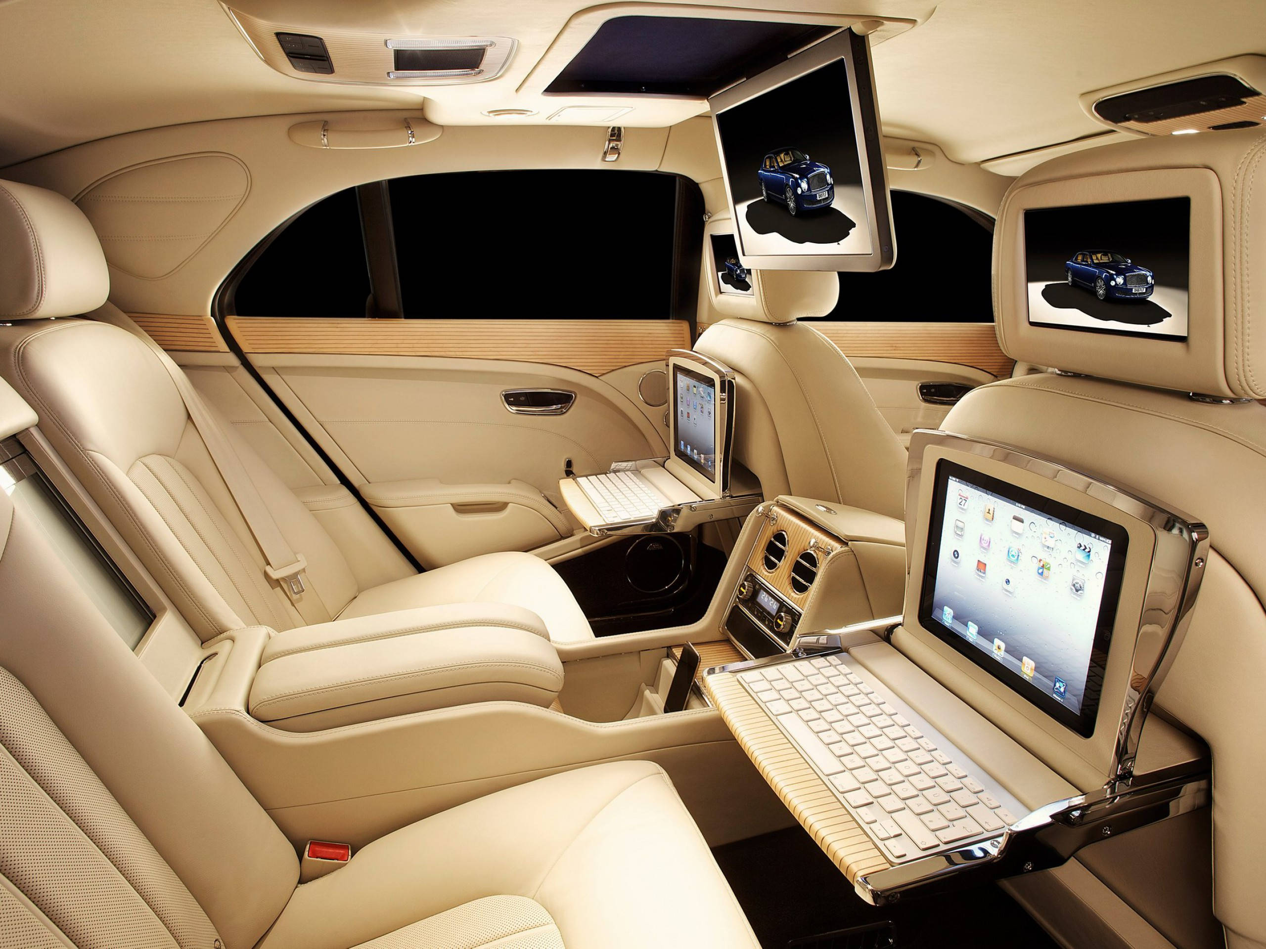 bentley HD 桌布 壁紙 — 豪華車內飾，配備奶油色皮革座椅和為後排乘客內置的筆記本電腦和螢幕。