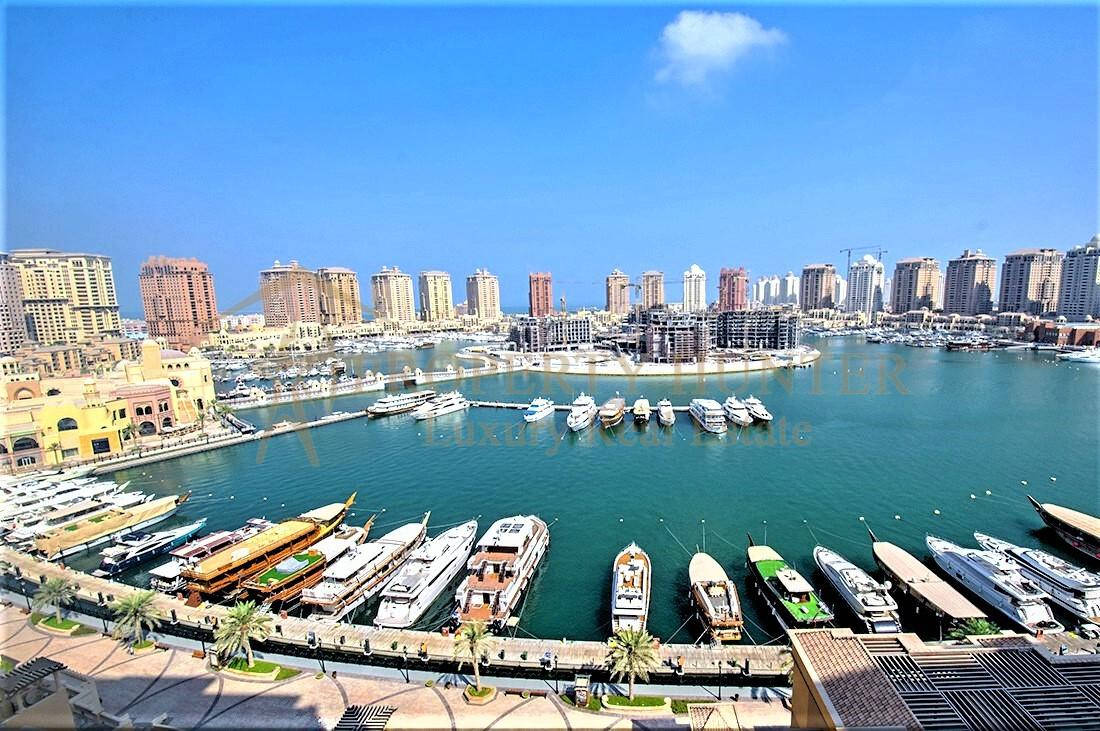 Qatar 桌布 壁紙 — 豪華遊艇碼頭的鳥瞰圖，停滿了遊艇和傳統船隻，藍天白雲下，現代摩天大樓沿著海濱排列。