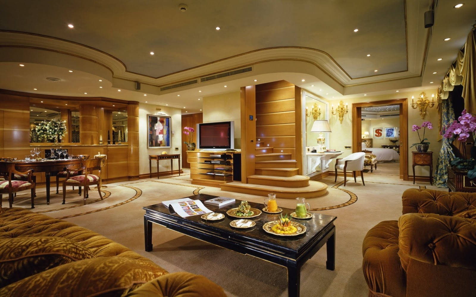 Interior Design 桌布 壁紙 — 豪華酒店套房，配有金色天鵝絨家具、木質裝飾，以及溫暖環境燈光下的優雅用餐區。