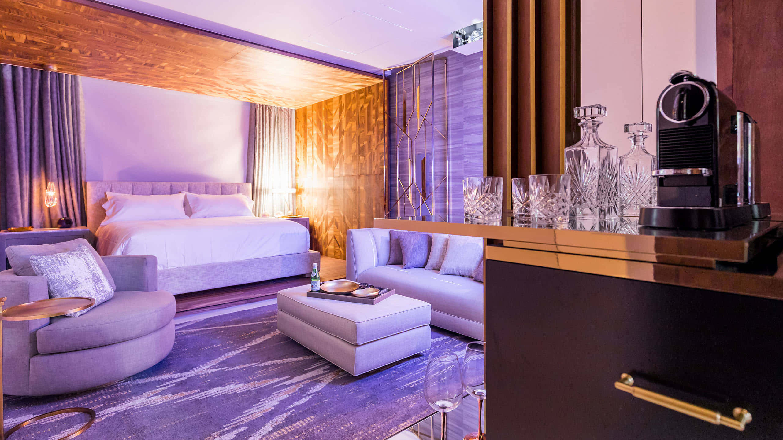 Bedroom 桌布 壁紙 — 豪華酒店客房沐浴在紫色環境光中，配備現代家具和時尚酒吧區。