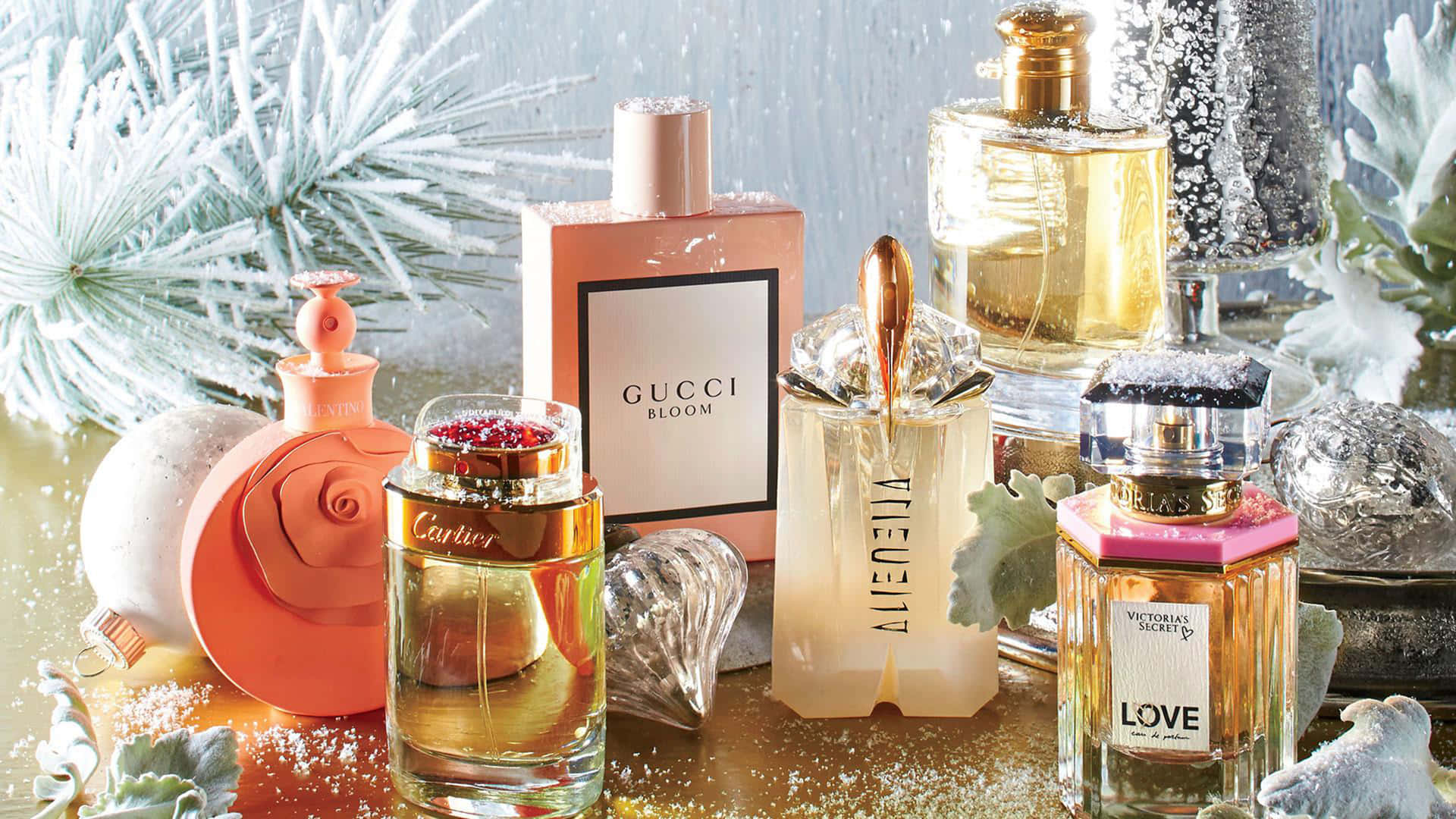 Gucci 桌布 壁紙 — 豪華香水瓶在柔和光線下閃耀，周圍是白雪覆蓋的松樹枝和閃閃發光的裝飾品。