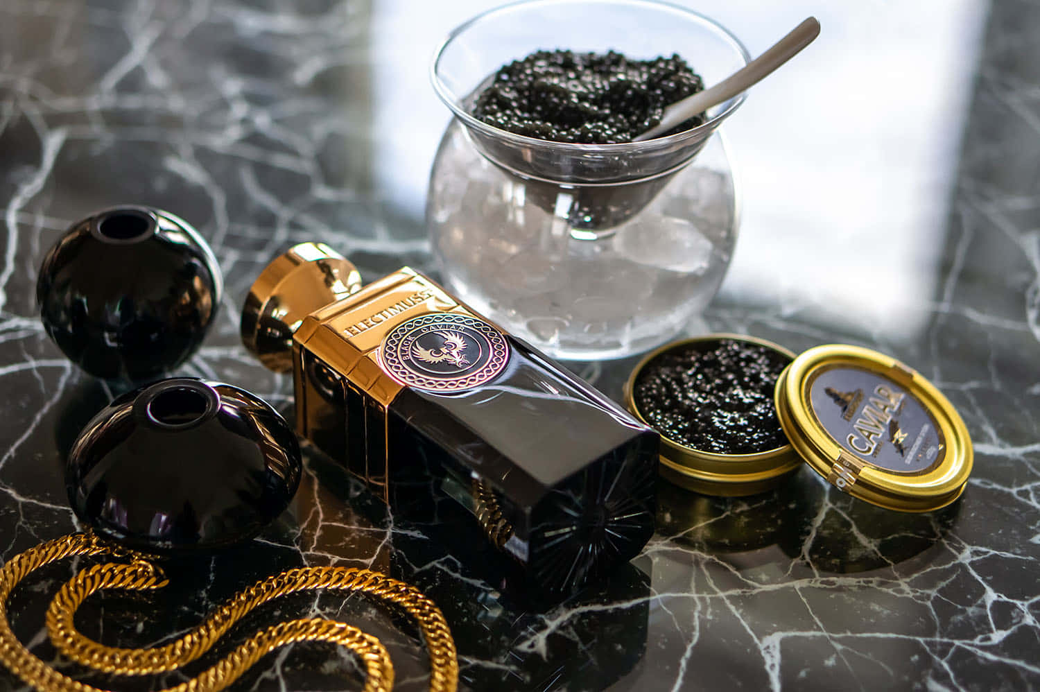 Black Caviar 桌布 壁紙 — 豪華黑魚子醬與黃金首飾優雅地擺放在帶有冰塊的深色大理石表面上。