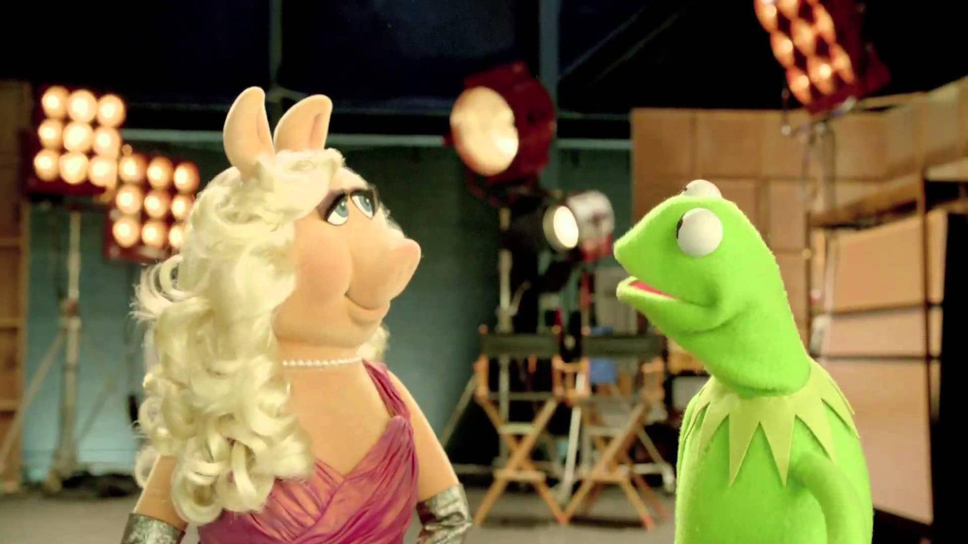 Miss Piggy 桌布 壁紙 — 豬小姐和青蛙柯米特在溫暖照明的後台工作室中面對面，可見燈光設備和導演椅。