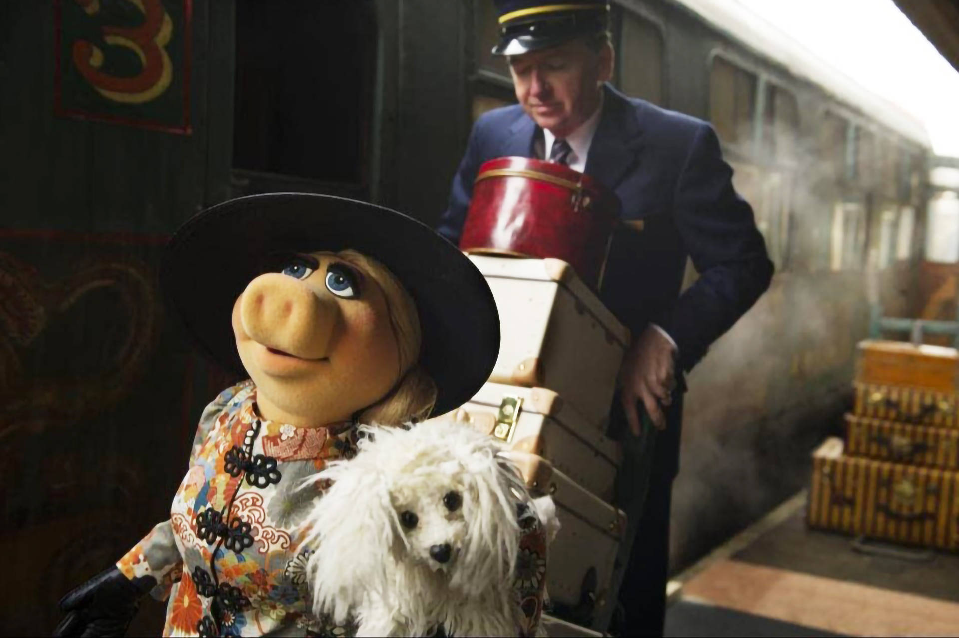muppets 桌布 壁紙 — 豬小姐穿著花卉圖案連衣裙和黑色帽子，在蒸汽火車站抱著一隻毛茸茸的白狗，附近有一位列車長。