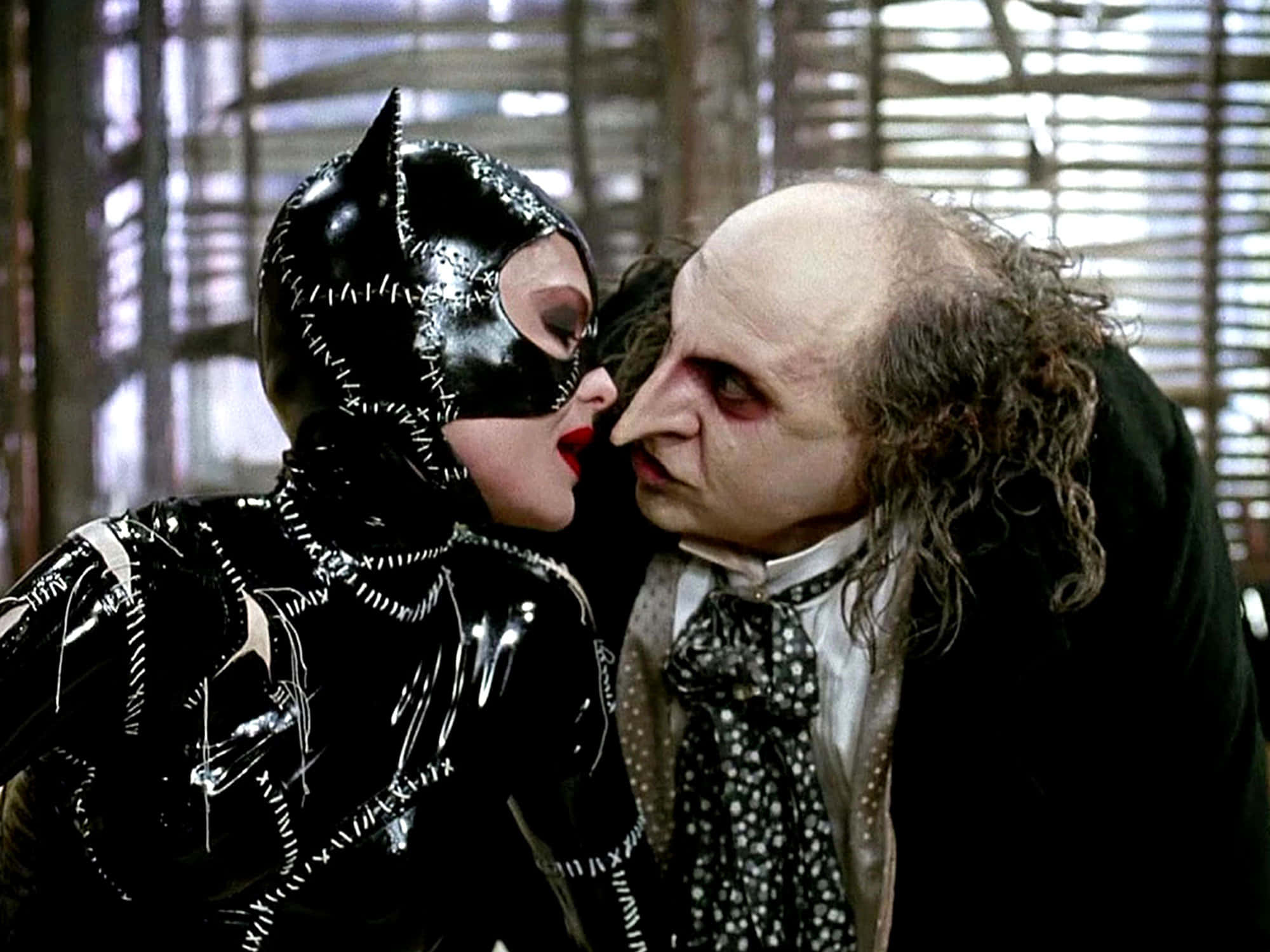 Batman Penguin 桌布 壁紙 — 貓女戴著黑色皮革面具，在昏暗的房間裡靠近臉色蒼白、捲髮的蝙蝠俠反派。
