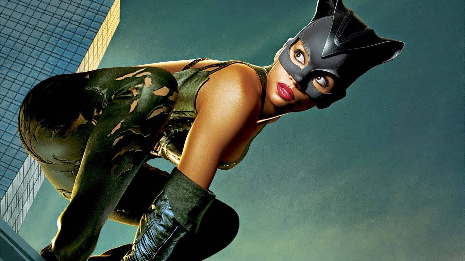 Catwoman 桌布 壁紙 — 貓女穿著時尚的黑色和綠色套裝，蹲在摩天大樓的邊緣，背景是青綠色的天空。