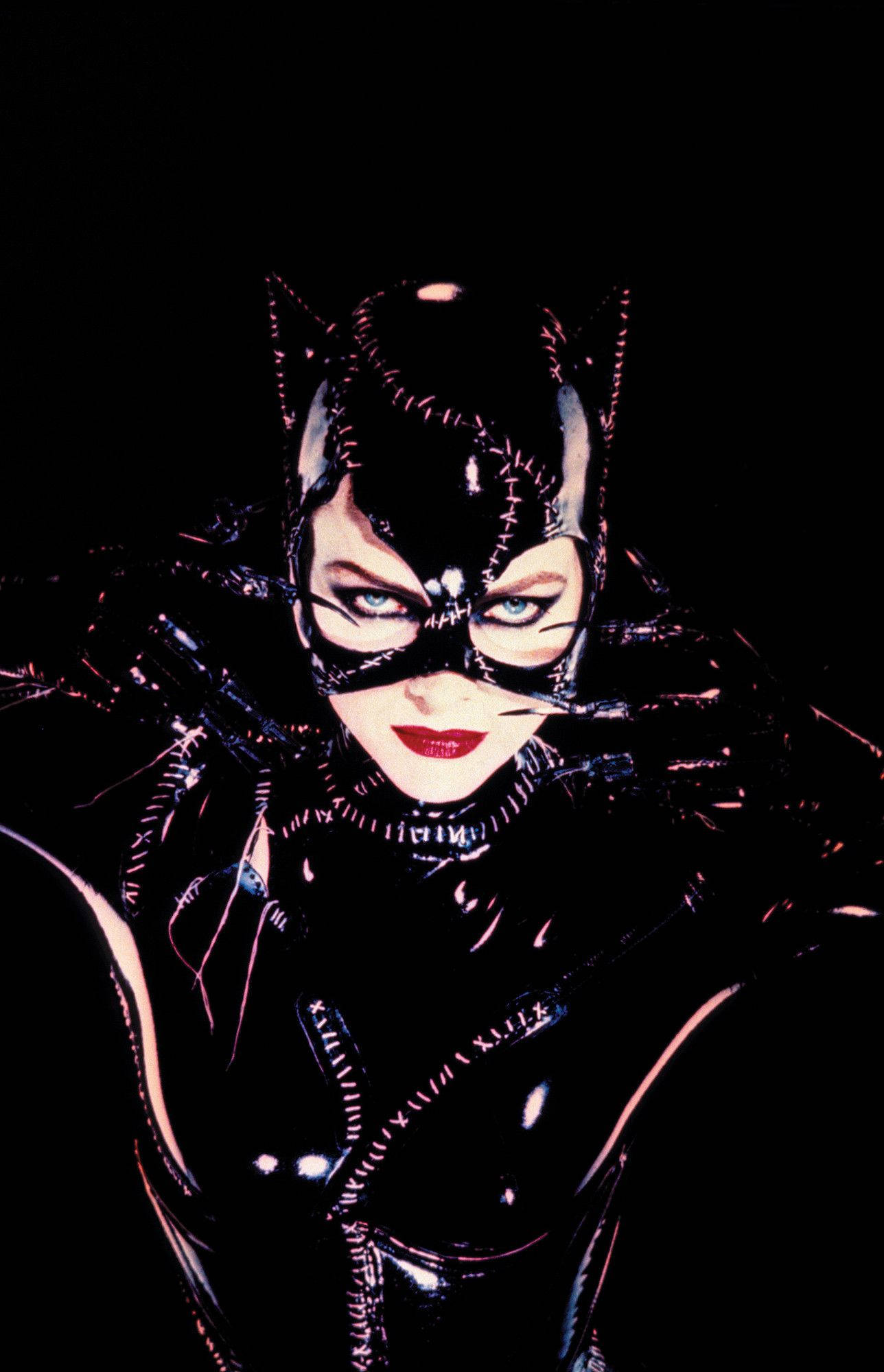 Catwoman 桌布 壁紙 — 貓女近距離特寫，身穿亮黑色套裝，戴著貓耳，紅唇，背景深色。