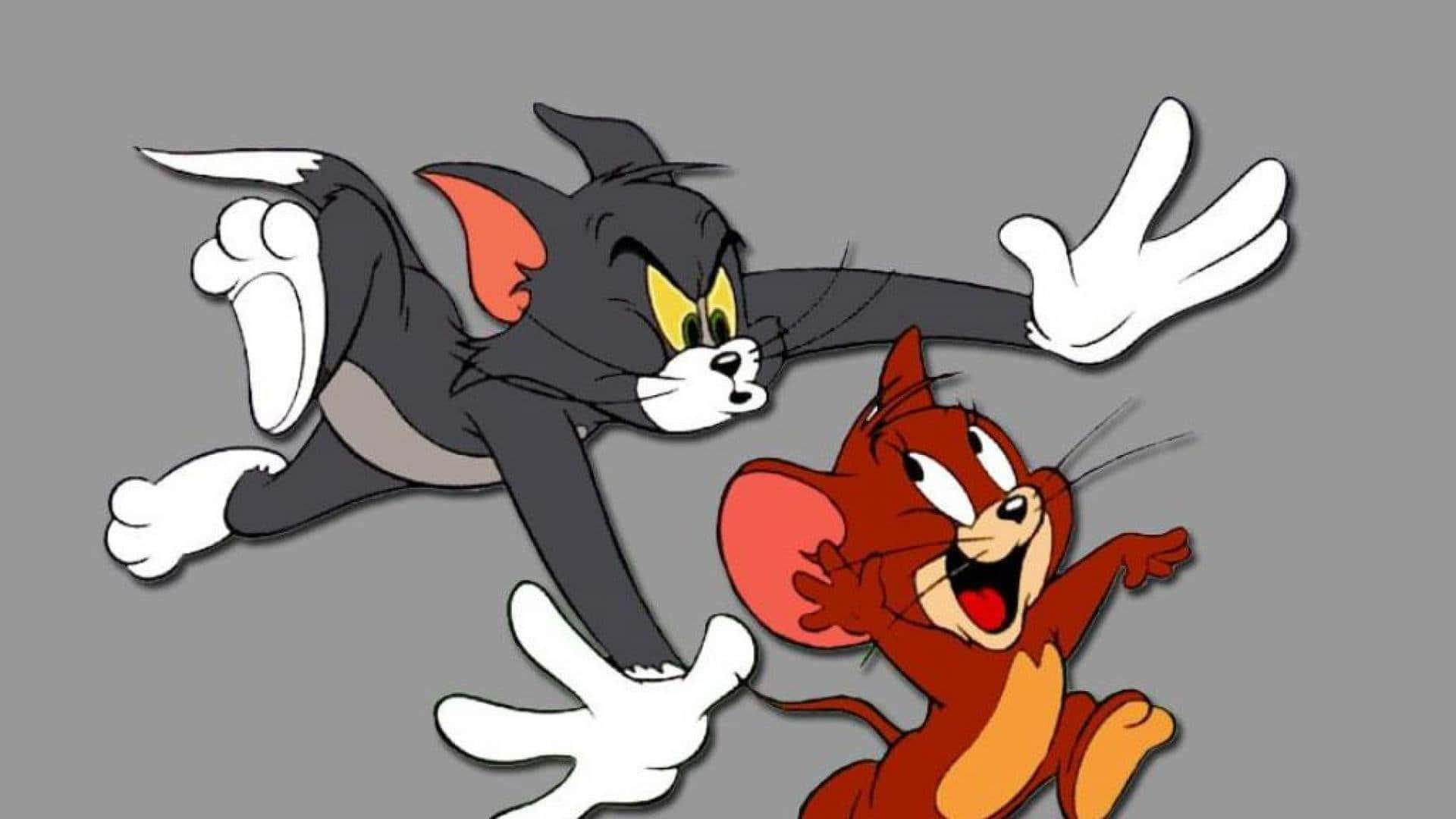 Tom And Jerry Funny 桌布 壁紙 — 貓湯姆搞笑地撲向老鼠傑瑞，傑瑞在純灰色背景上勝利地大笑。