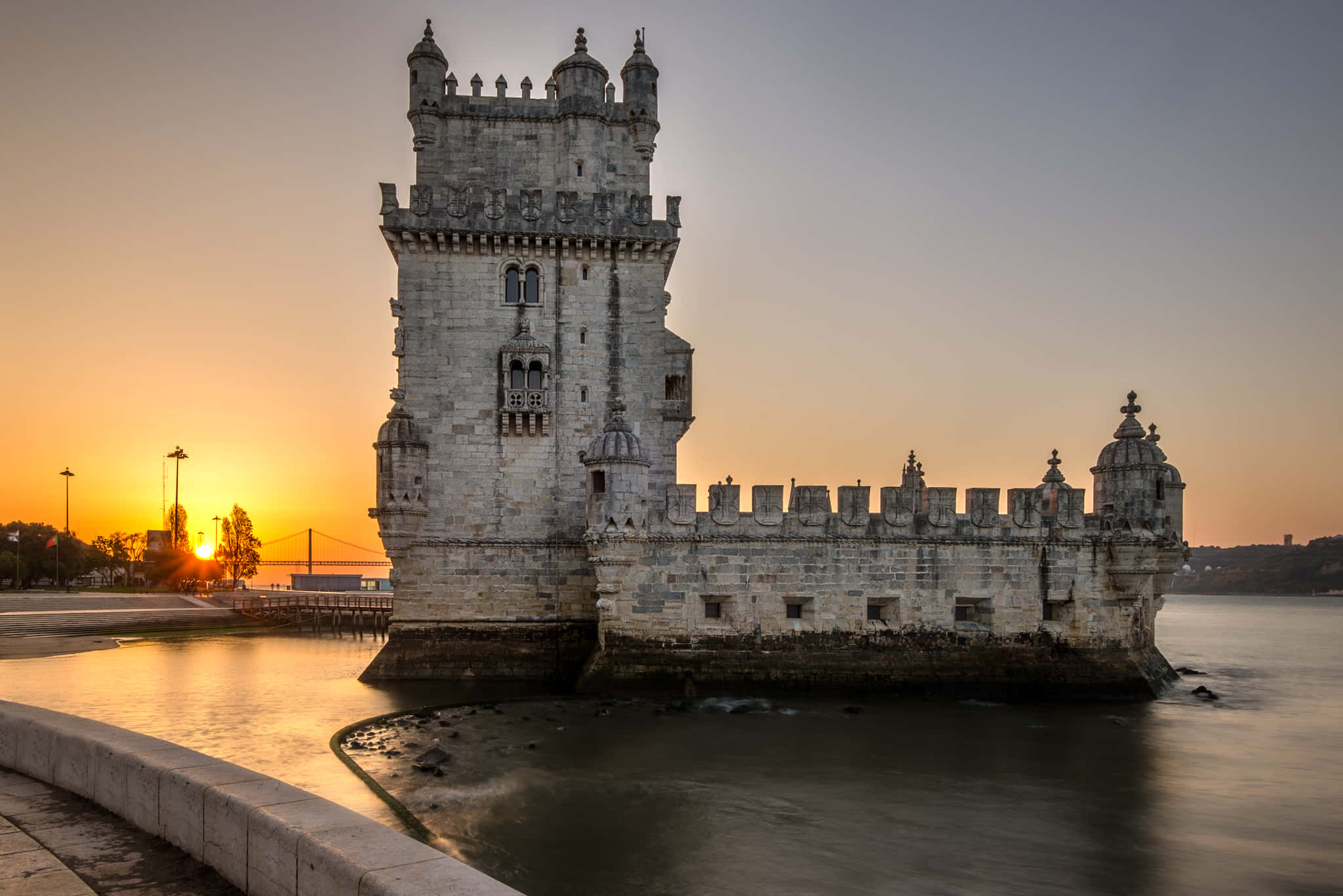 Portugal 桌布 壁紙 — 貝倫塔在日落時分巍然聳立，其石牆在平靜的水面上反射出金色的光芒。