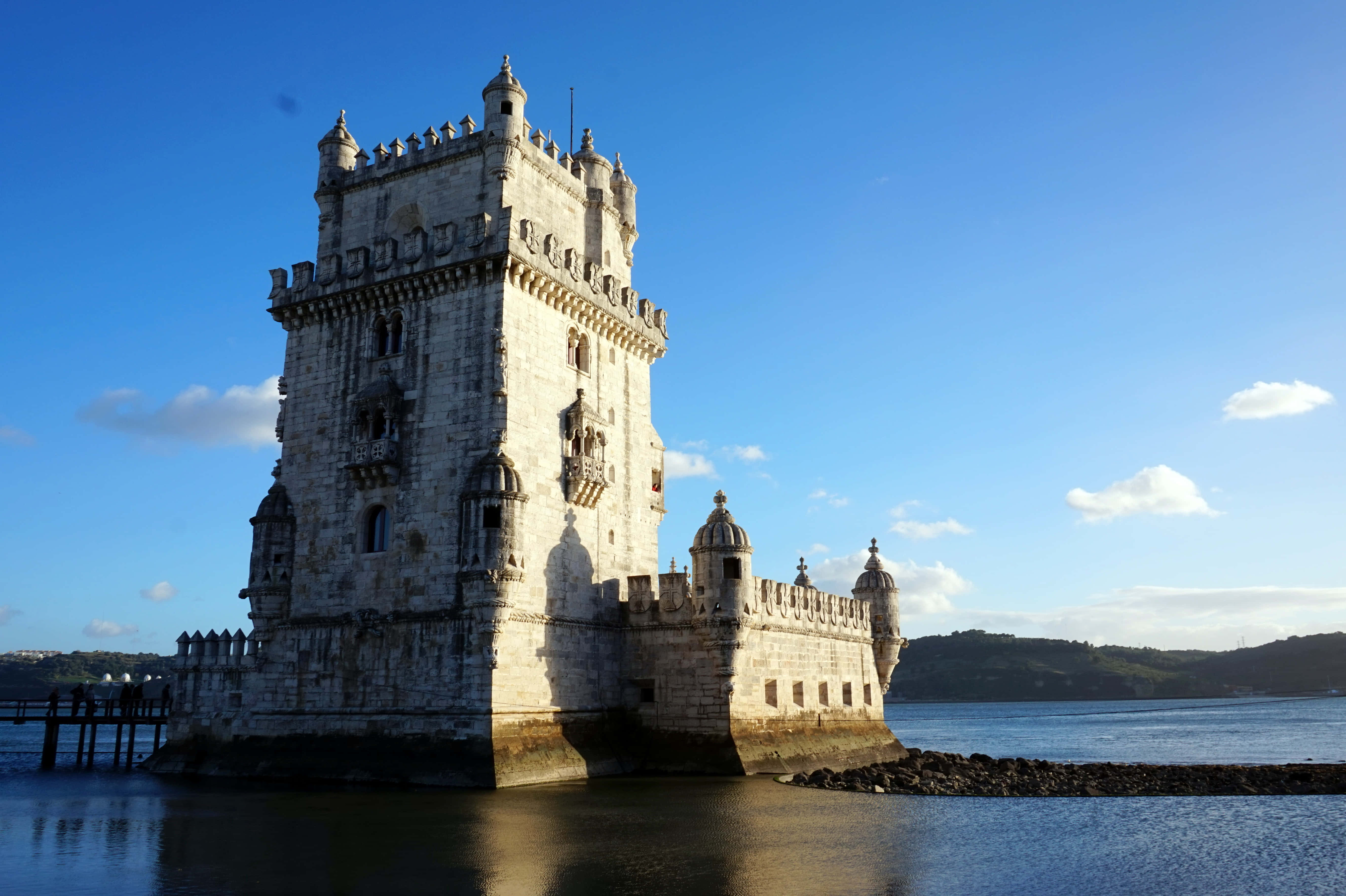 Portugal 桌布 壁紙 — 貝倫塔在清澈藍天和零星白雲下，雄偉地矗立在水面上。