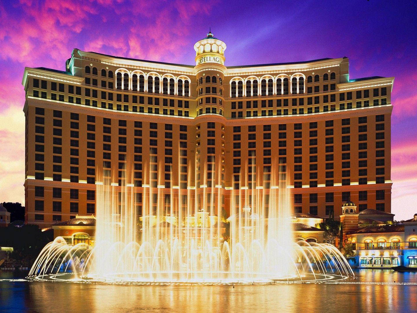 Las Vegas 桌布 壁紙 — 貝拉吉奧酒店在充滿活力的紫色日落中溫暖地發光，其標誌性噴泉以同步的弧線噴出金色的水。