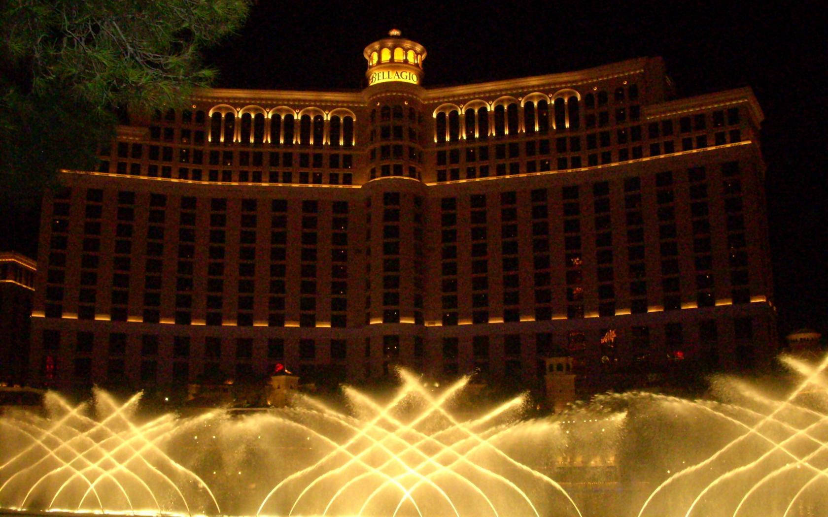 Las Vegas 桌布 壁紙 — 貝拉吉奧酒店在夜晚散發溫暖光芒，金色燈光照亮其外牆及下方同步噴泉。