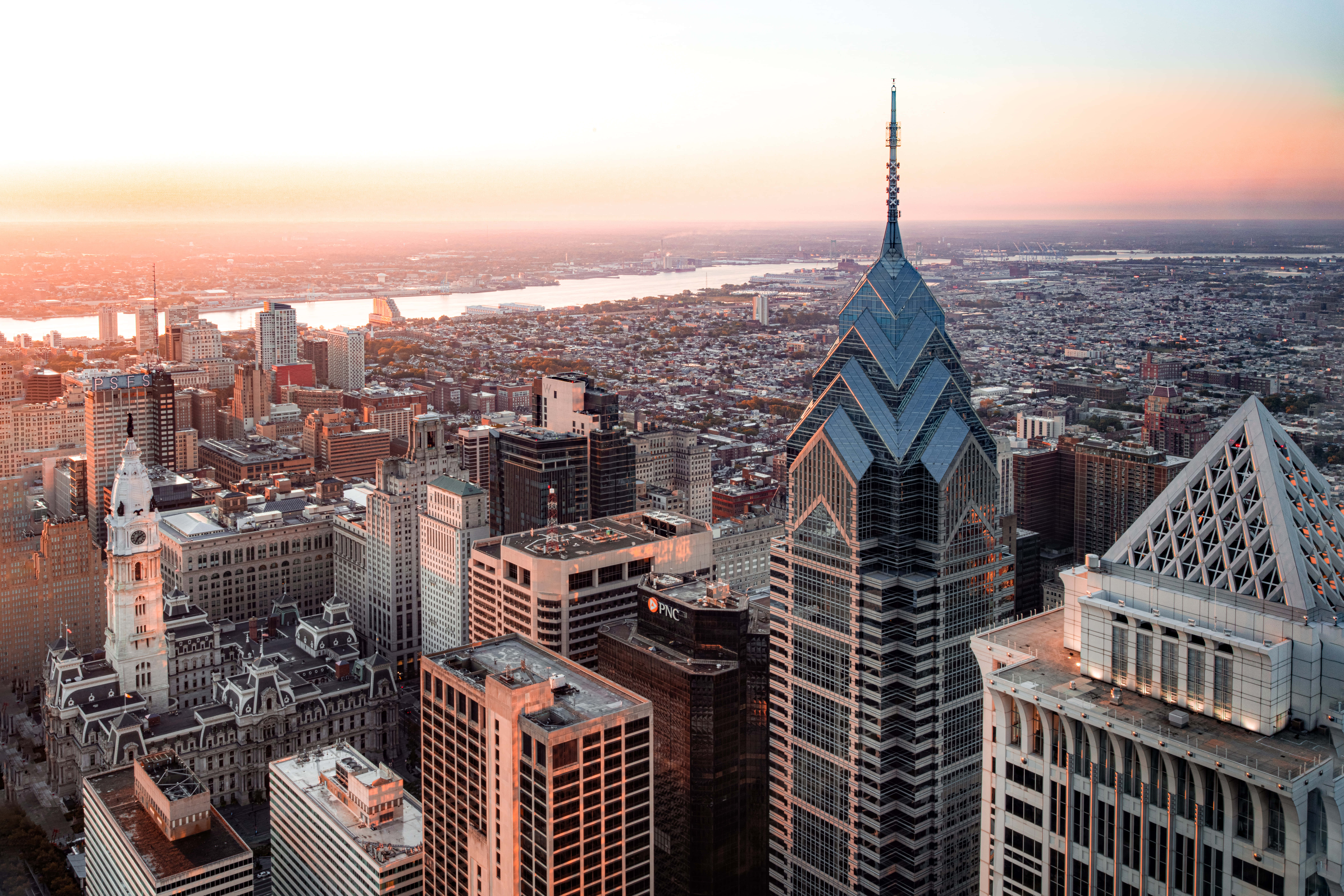 Philly 桌布 壁紙 — 費城天際線的鳥瞰圖，夕陽西下，金色光芒沐浴著摩天大樓和下方的河流。