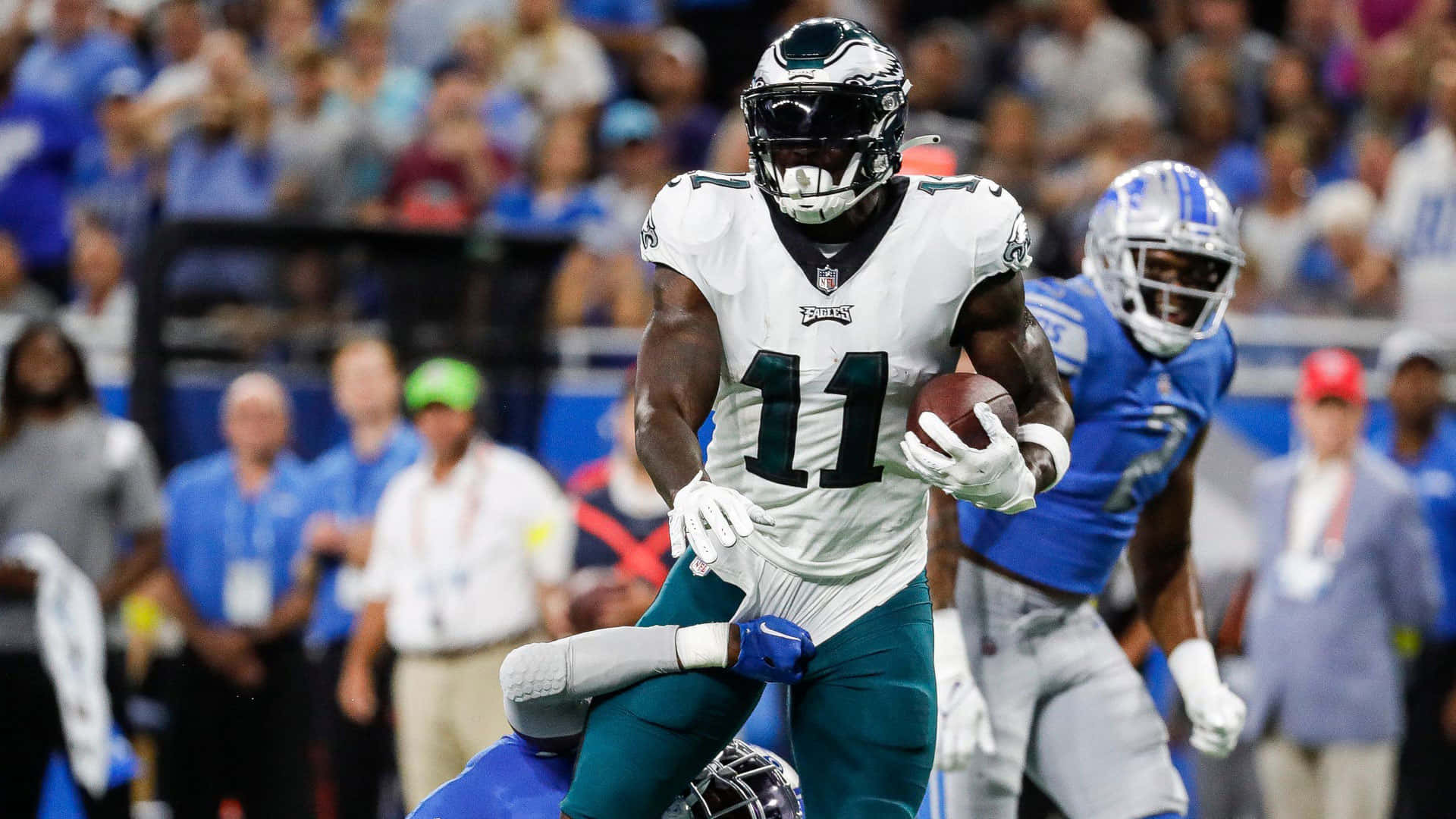 NFL Teams 桌布 壁紙 — 費城老鷹隊11號球員在夜間比賽中帶著足球衝刺，底特律雄獅隊防守球員逼近。