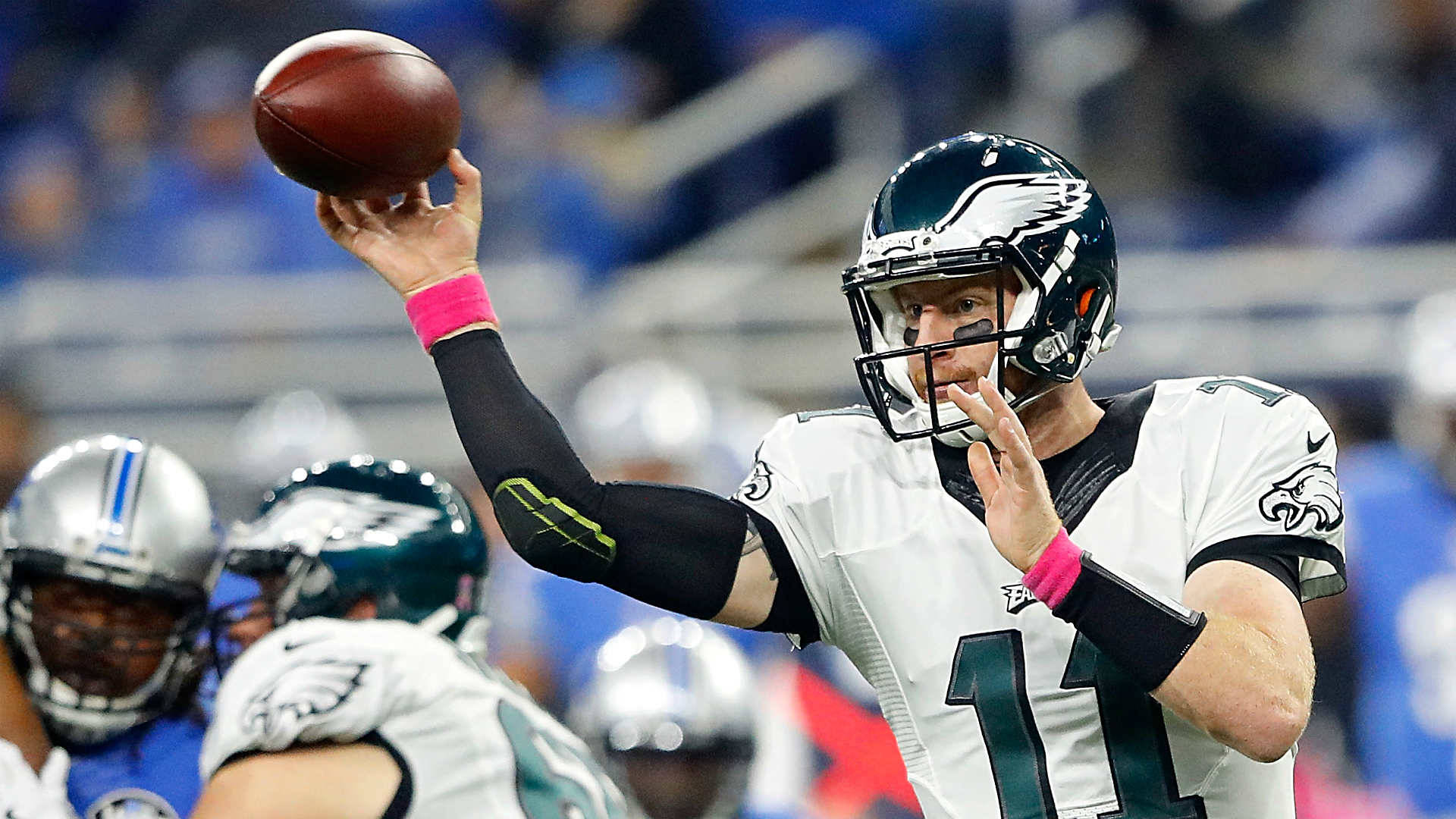 運動 桌布 壁紙 — 費城老鷹隊的四分衛身穿白色11號球衣，在NFL日間比賽中準備傳球，背景有隊友和模糊的體育場。