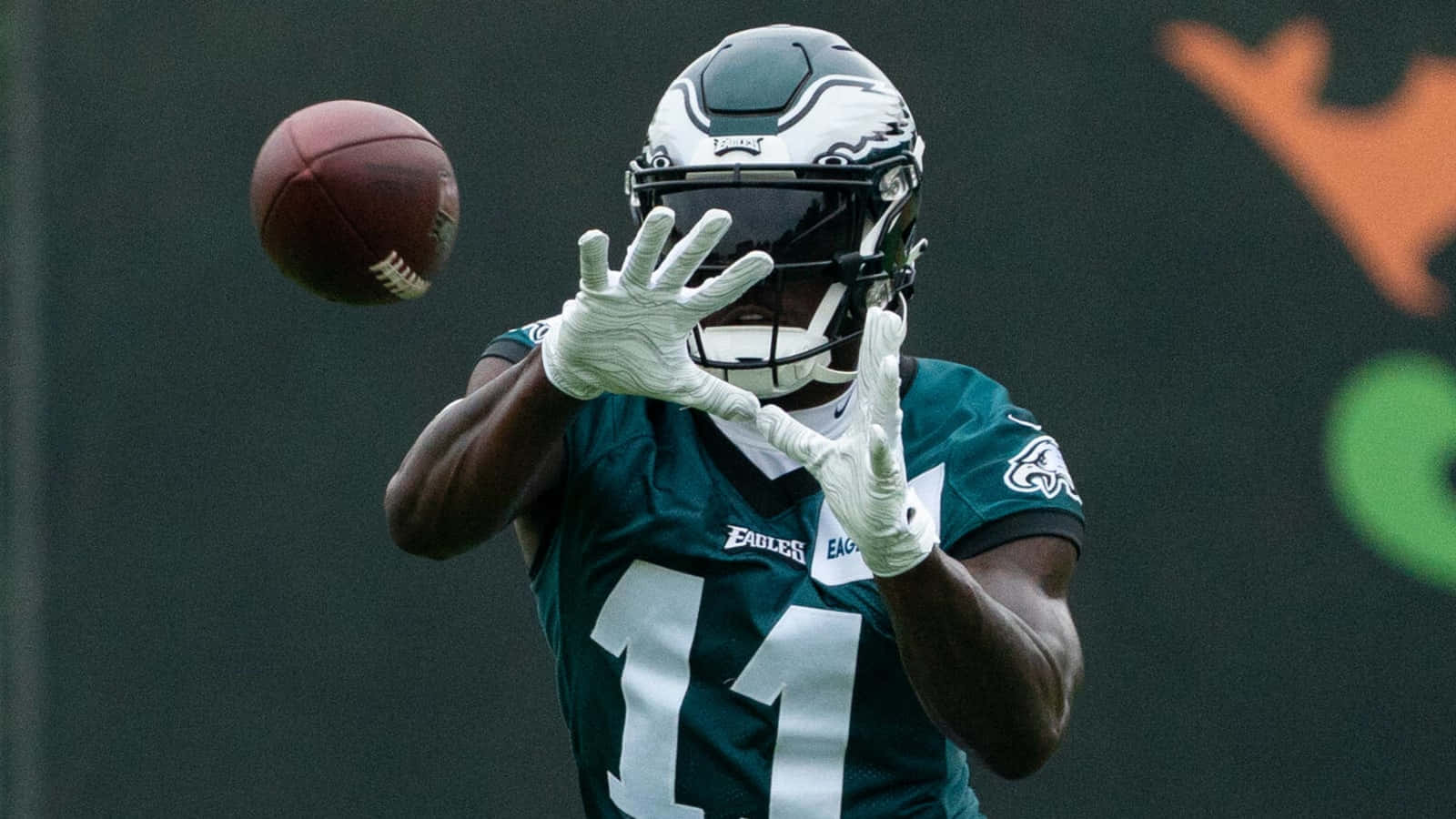 Eagles 桌布 壁紙 — 費城老鷹隊的美式足球員身穿青綠色11號球衣，戴著白色手套跳起接住半空中的棕色美式足球。