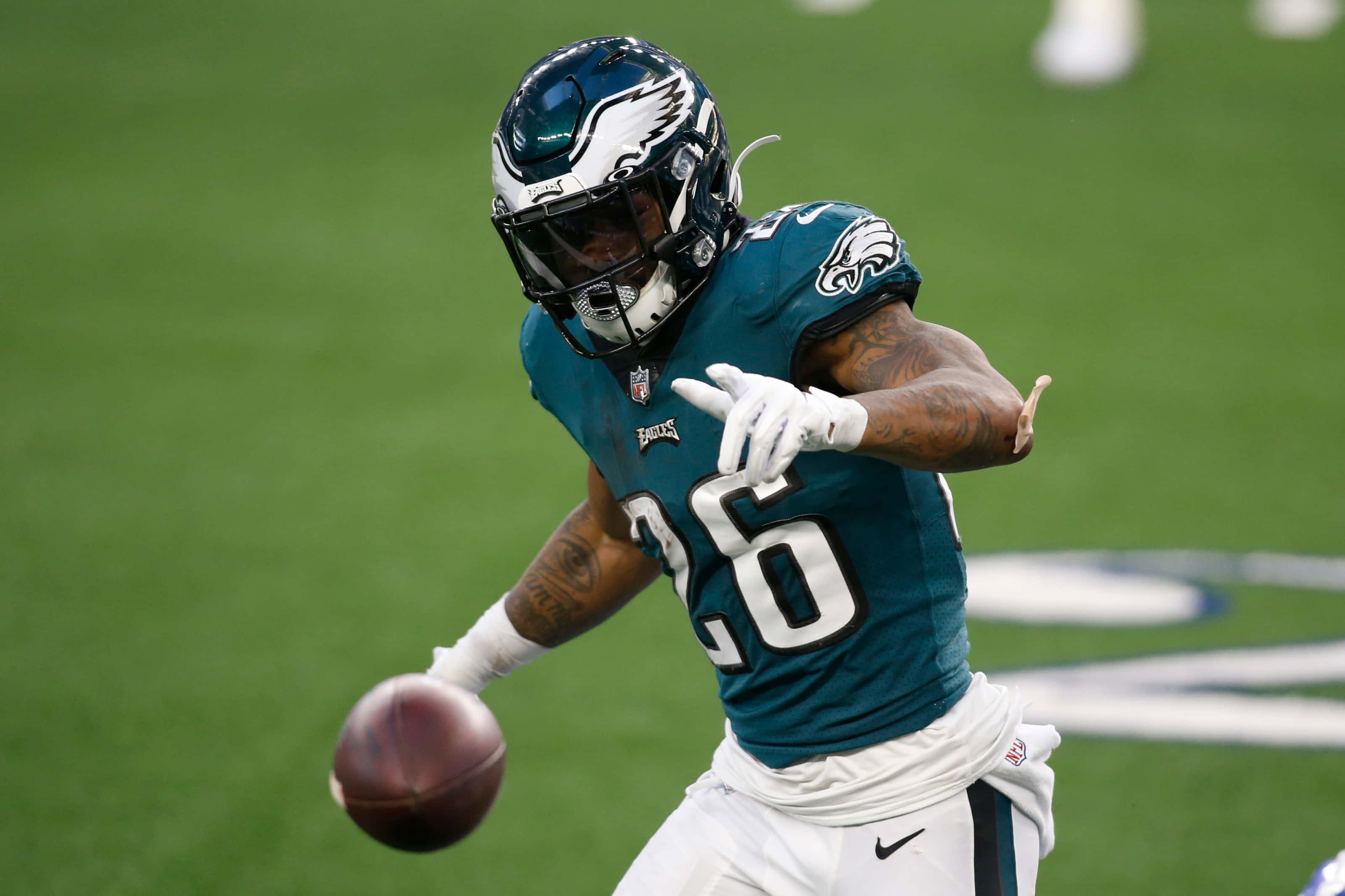 Miles Sanders 桌布 壁紙 — 費城老鷹隊美式足球員16號身穿青綠色和白色球衣在綠色球場上接住一個足球。