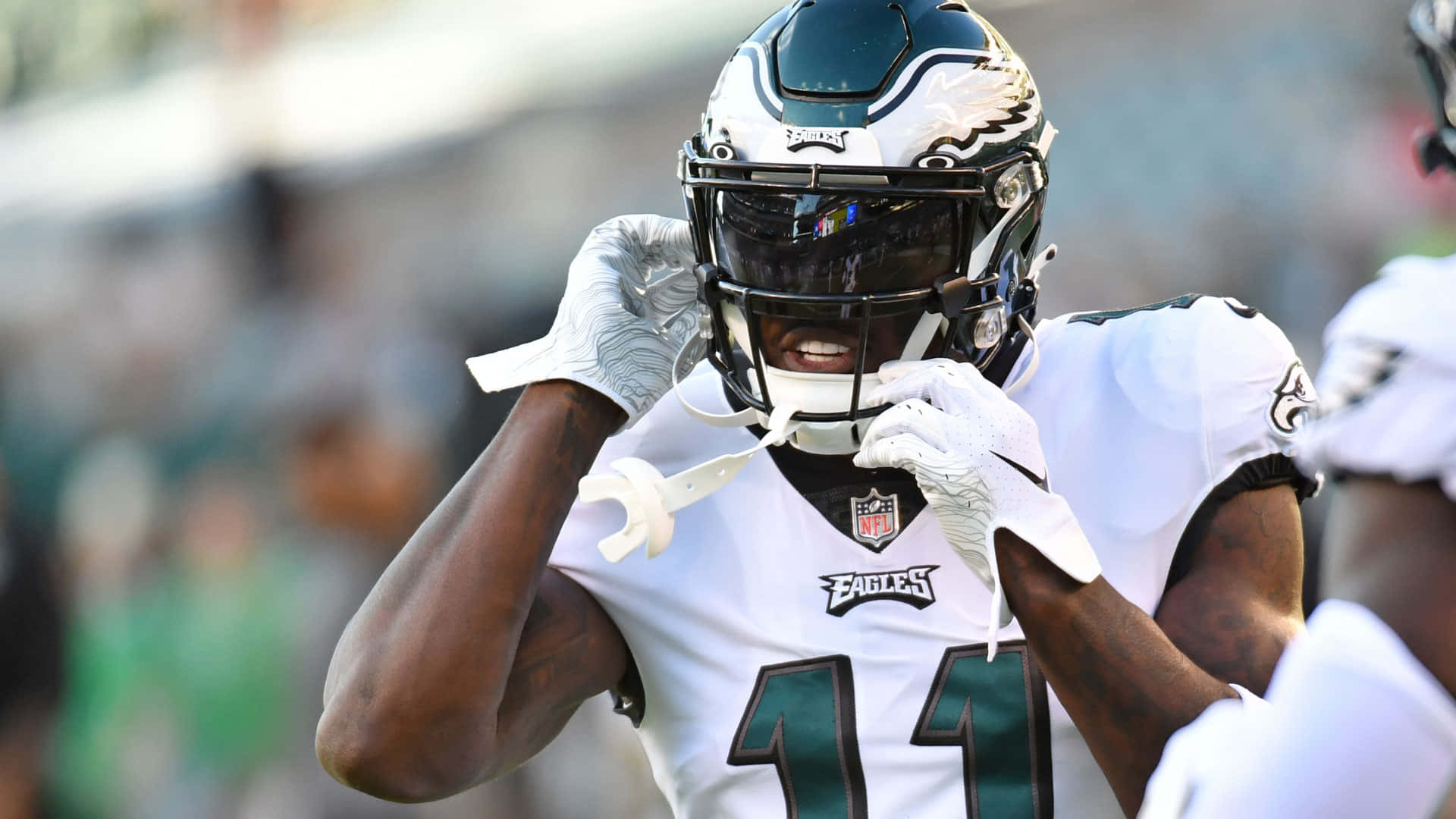 NFL 桌布 壁紙 — 費城老鷹隊美式足球員身穿白色11號球衣，在日間比賽中調整頭盔。