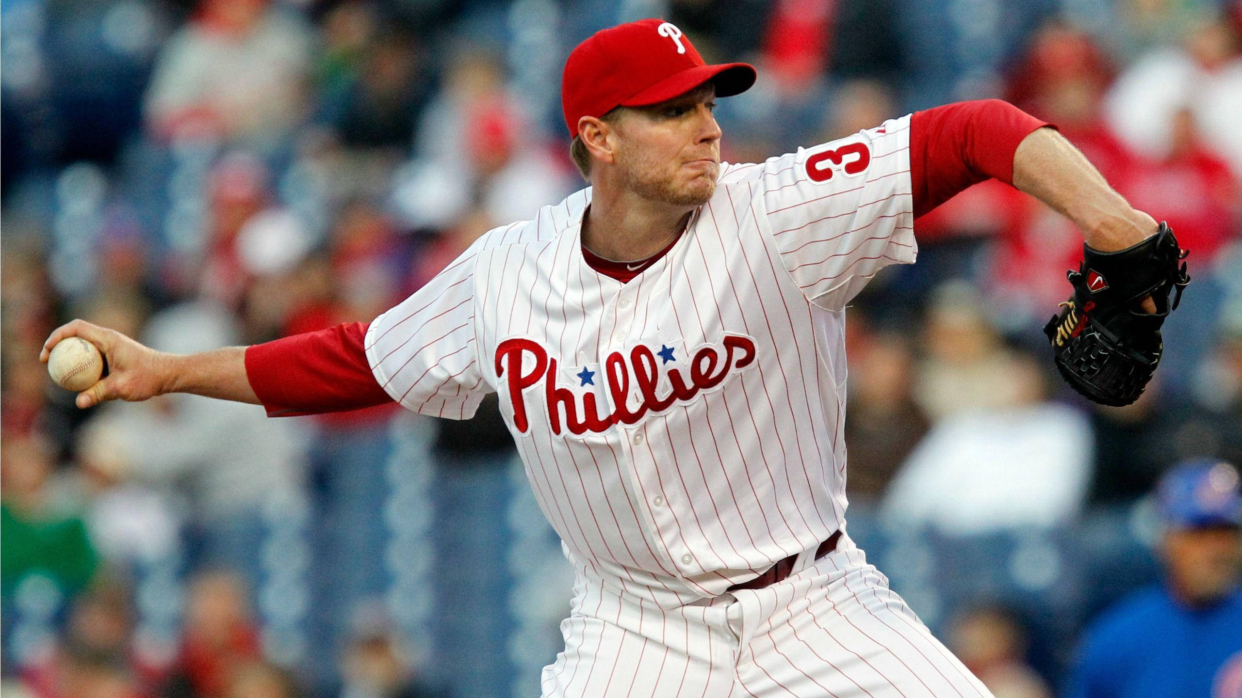 roy halladay 桌布 壁紙 — 費城費城人隊投手在日間棒球比賽中投球，背景是模糊的體育場人群。