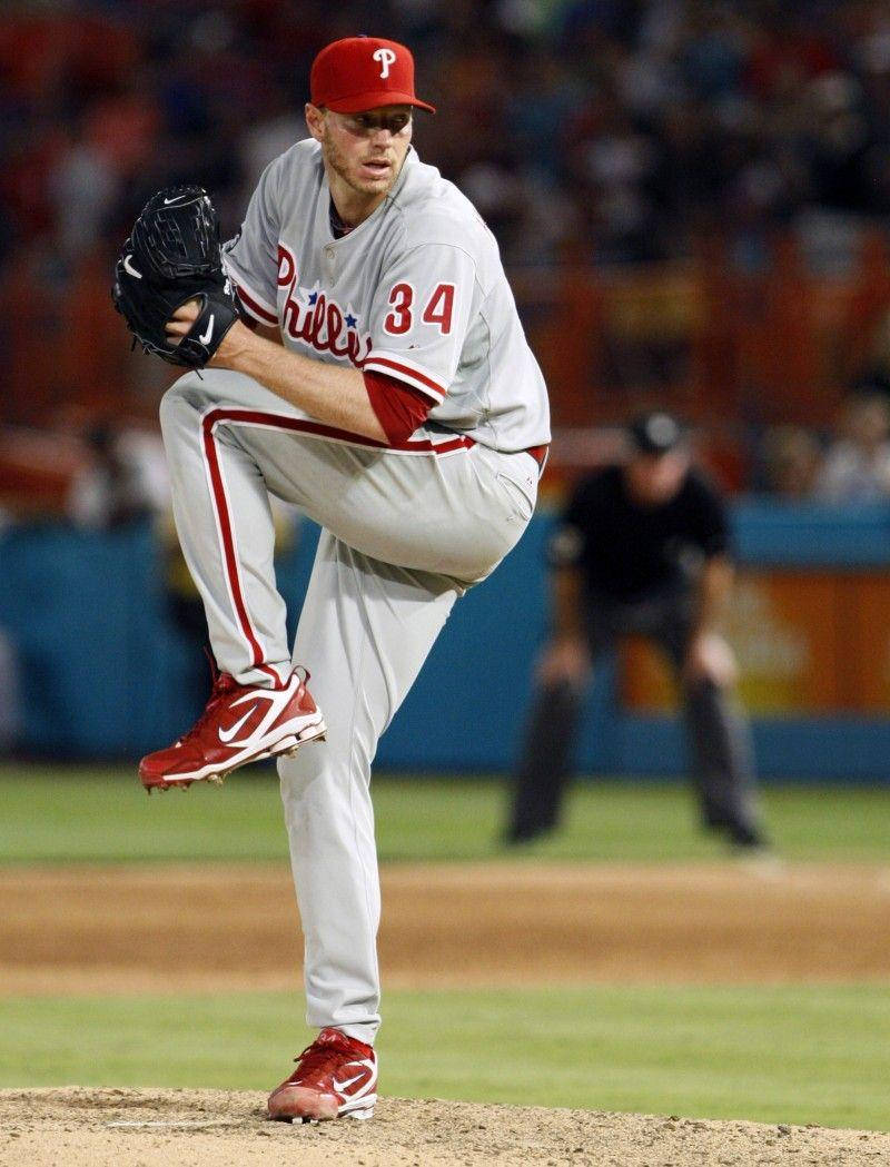 roy halladay 桌布 壁紙 — 費城費城人隊投手在球場燈光下於投手丘上投球，背景有模糊的人群。