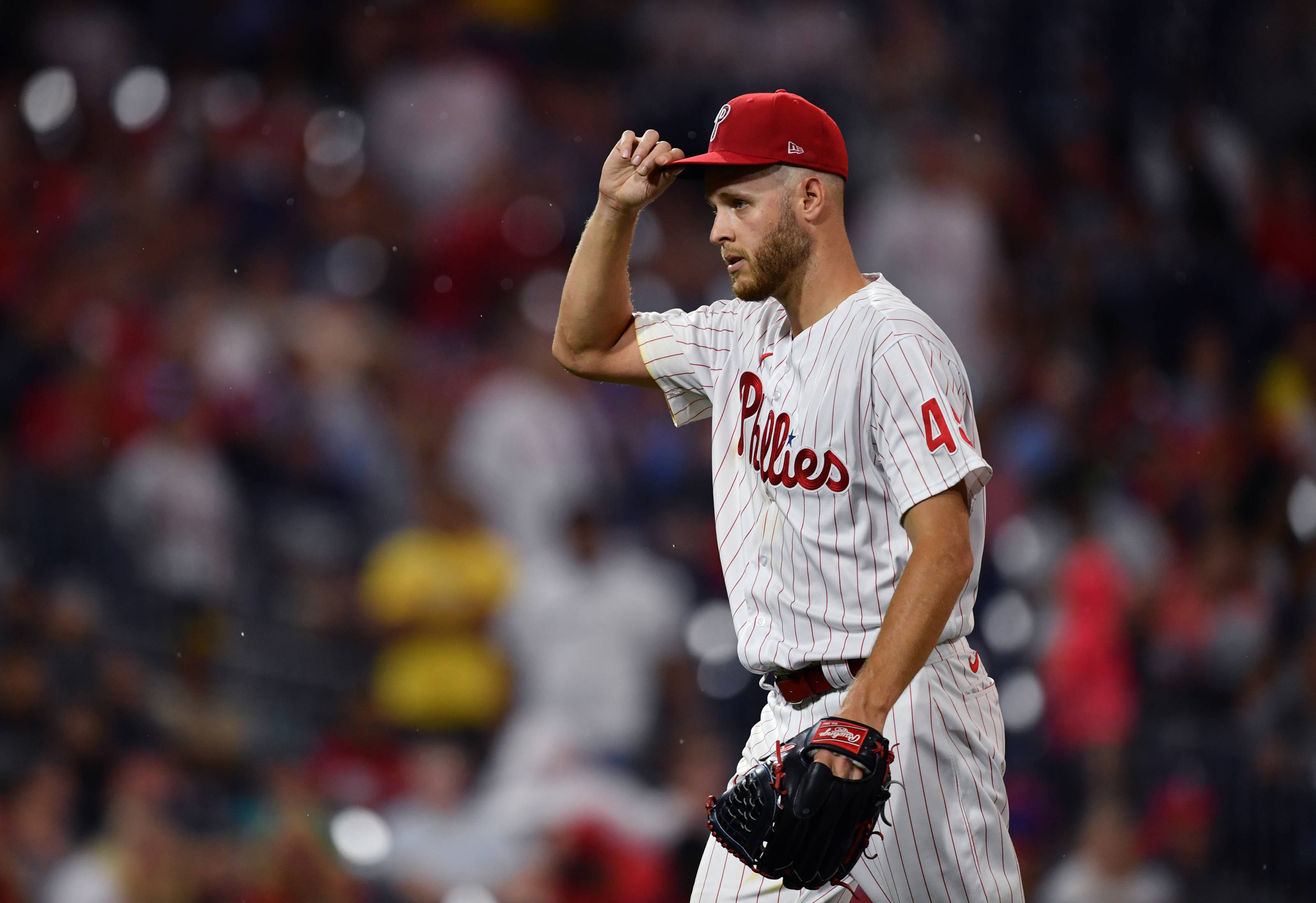 Phillies 桌布 壁紙 — 費城費城人隊的棒球投手穿著白色細條紋制服，在夜間比賽的球場燈光下調整他的紅色帽子。